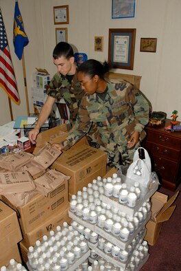 36th Communications Squadron dormitory residents Airmen First Class Zachary Hunter and Monica Cooper select Meals Ready to Eat and bottled water Monday as dorm rations for the coming storm. (U.S. Air Force photo by Tech. Sgt. Michael Boquette)