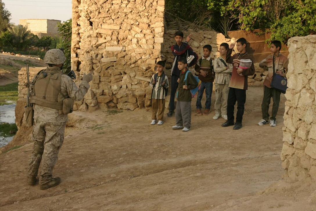 A Marine assigned to Bravo Company, 1/3, speaks with children while on a patrol in Haditha City April 10. The children are very important to the 1/3 mission and Marines often hand out candy and school supplies to the children to show they are here to help.