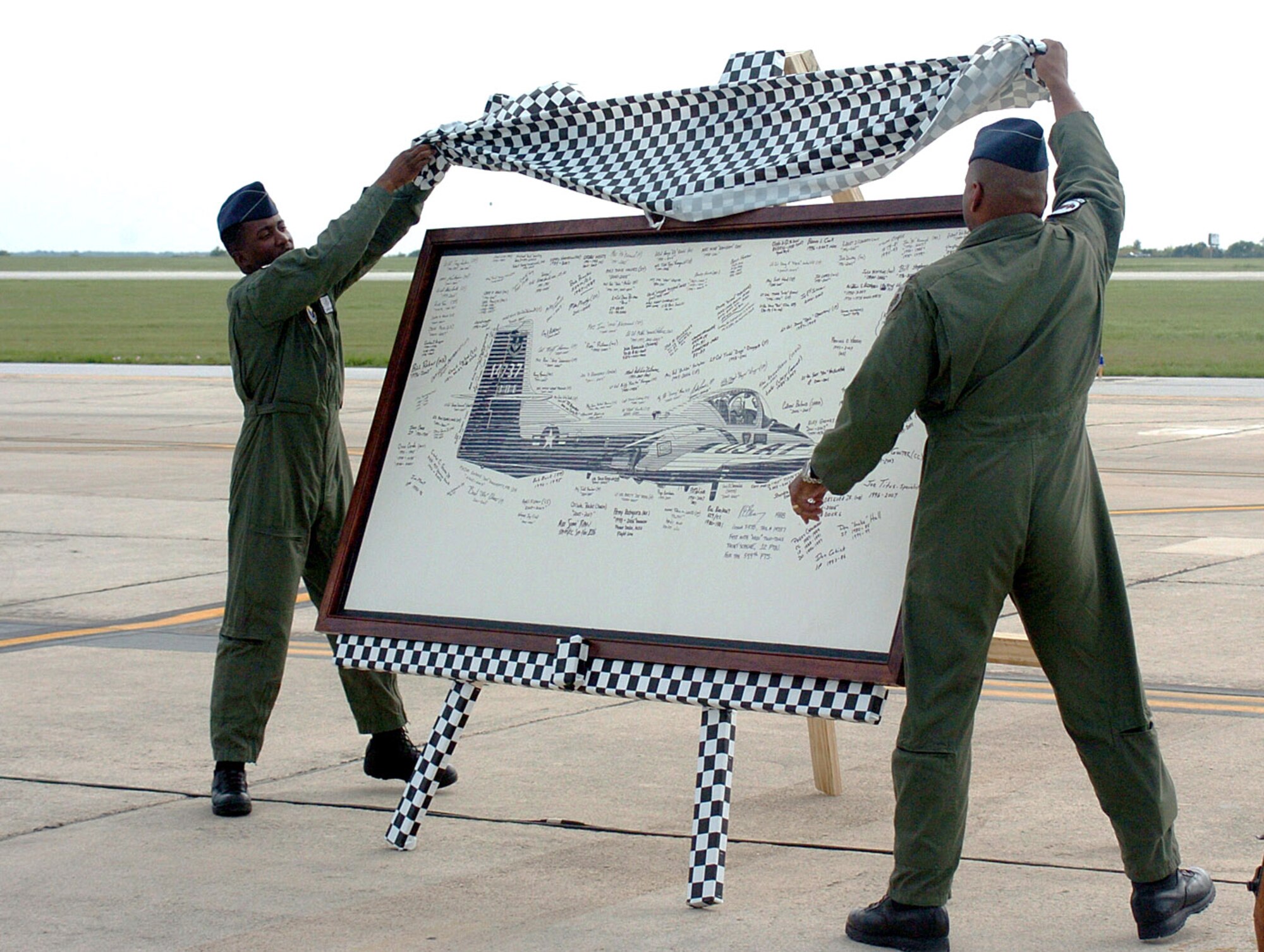 Maj. Marico Tippett (left), 559th Flying Training Squadron, and Col. Richard Clark, 12th Flying Training Wing commander, reveal the T-37 Heritage Board signed by former Tweet instructors, maintainers, life support and SARM personnel, during the T-37 Randolph retirement ceremony April 6. The board will be hung in the 559th FTS as a final tribute to the Tweet and those who supported its base mission. (U.S. Air Force photo/Dave Terry)