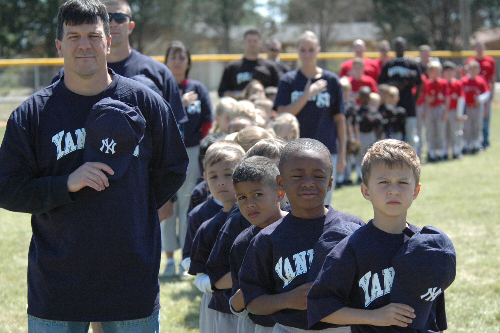 Tyndall youth baseball teams hold their hats over their hearts while the National Anthem plays during opening day ceremonies April 7 at the Youth Center ball fields.  (U.S. Air Force photo by Chrissy Cuttita)