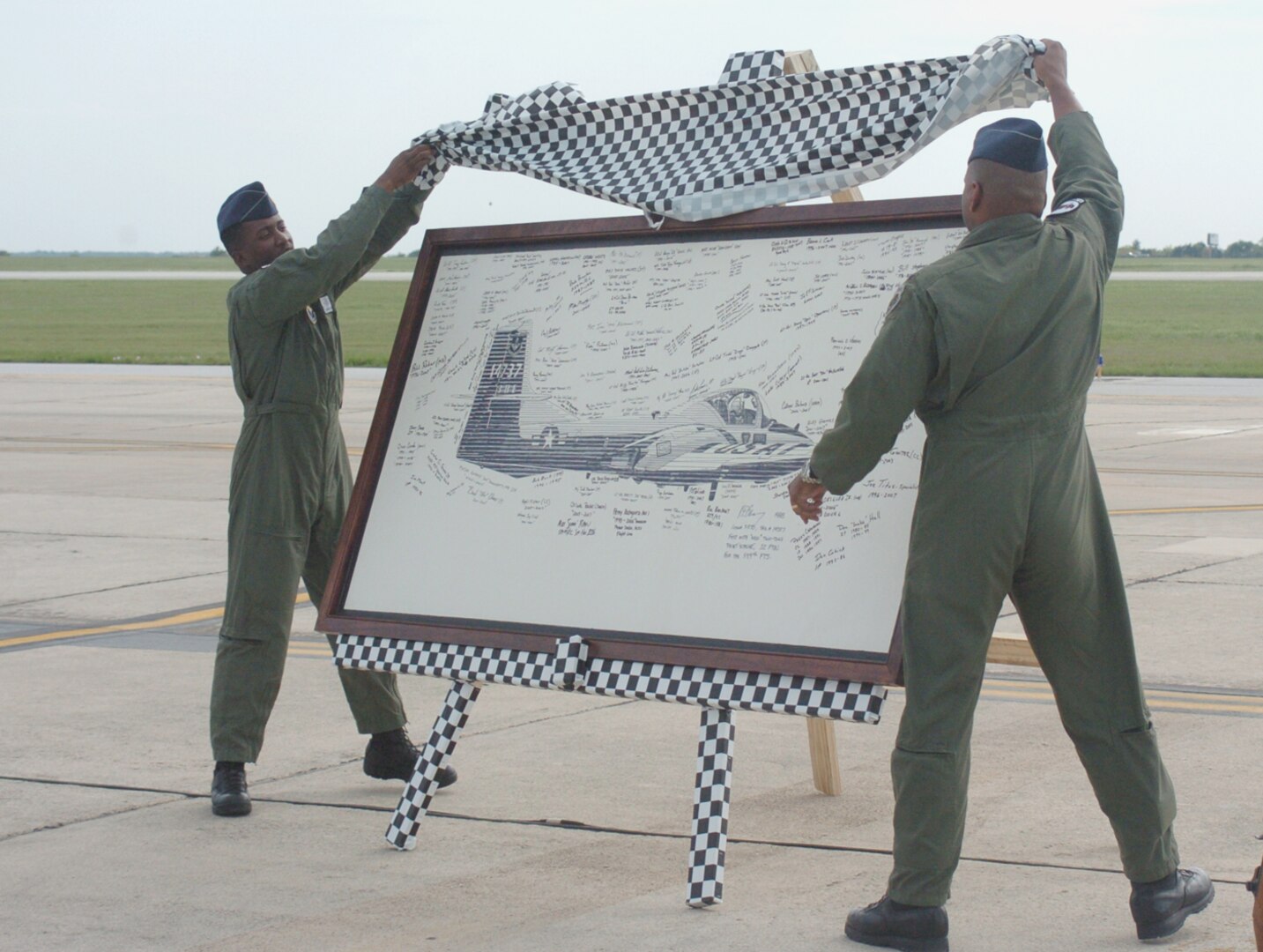 Maj. Marico Tippett (left), 559th Flying Training Squadron, and Col. Richard Clark, 12th Flying Training Wing commander, reveal the T-37 Heritage Board signed by former Tweet instructors, maintainers, life support and SARM personnel, during the T-37 Randolph retirement ceremony April 6. The board will be hung in the 559th FTS as a final tribute to the Tweet and those who supported its base mission. (U.S. Air Force photo by Dave Terry)