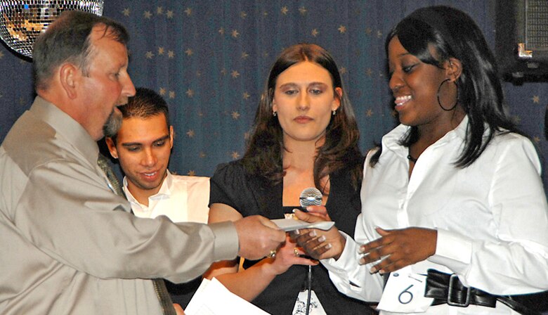 Larry Eccles, 377th Services Squadron, presents Airman 1st Class Brandi Lewis, 377th Mission Support Squadron, with a check for $25 after she placed third in the preliminary round of Kirtland Idol. Airman Lewis advances to the finals April 27. (U.S. Air Force photo by Adam Wooten)