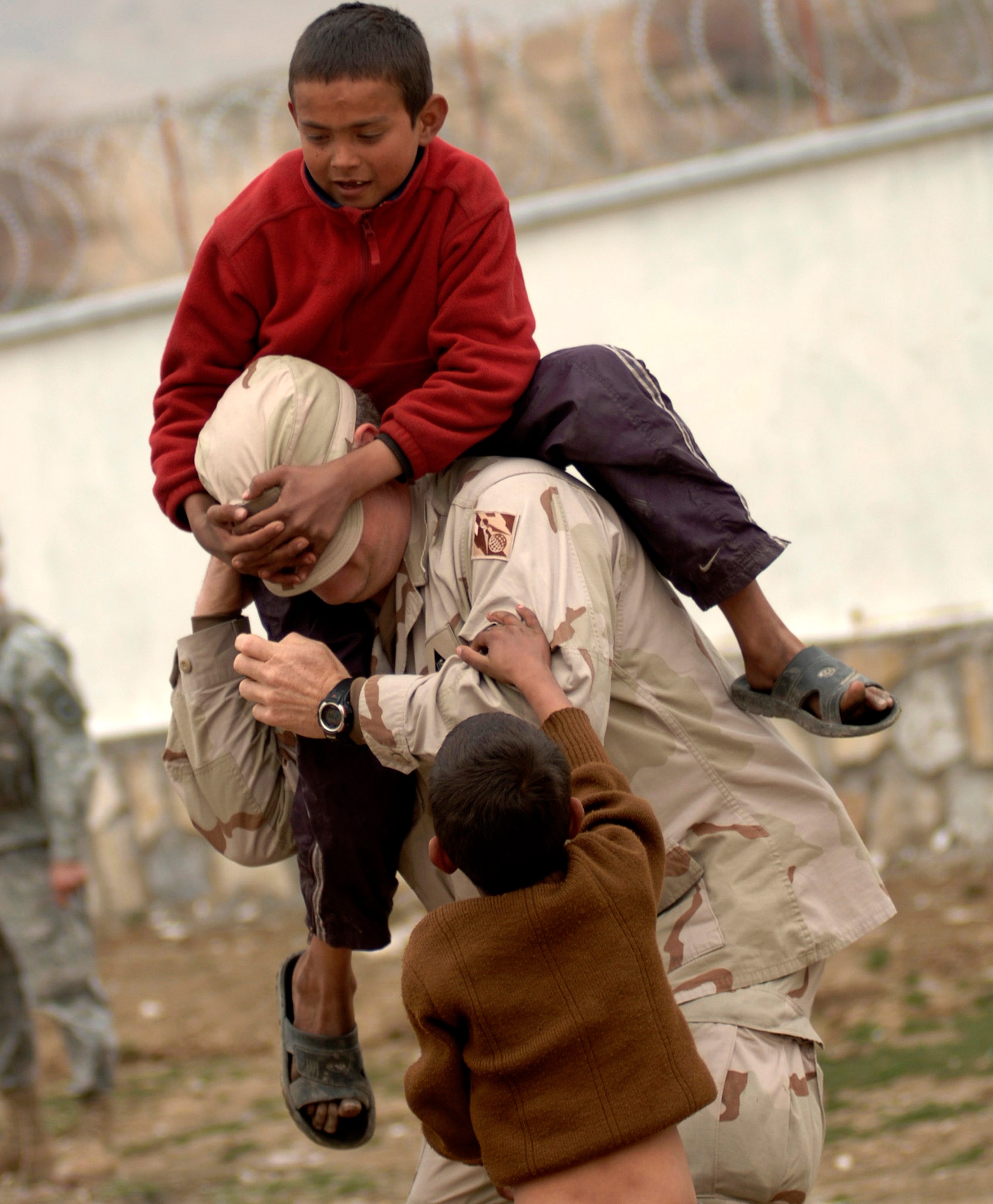 A Department of Defense civilian, supporting the Volunteer Community Reach Program in Kabul, Afghanistan, plays with refugee children April 8 in Dar Ul Aman. Volunteers of the outreach program provided a diversion for the children so that other volunteers could distribute, without distraction, 200 bags of clothes, shoes and toys donated from U.S. citizens. (U.S. Air Force photo/Tech. Sgt. Cecilio M. Ricardo Jr.)
