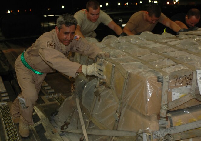 Master Sgt. Joe Maxey (left), 816th Expeditionary Airlift Squadron loadmaster helps push palletized cargo into a C-17 Globemaster from a 60K loader. Sergeant Maxey surpassed the milestone of 10,000 flying hours Tuesday. (U.S. Air Force photo by Senior Airman Erik Hofmeyer)