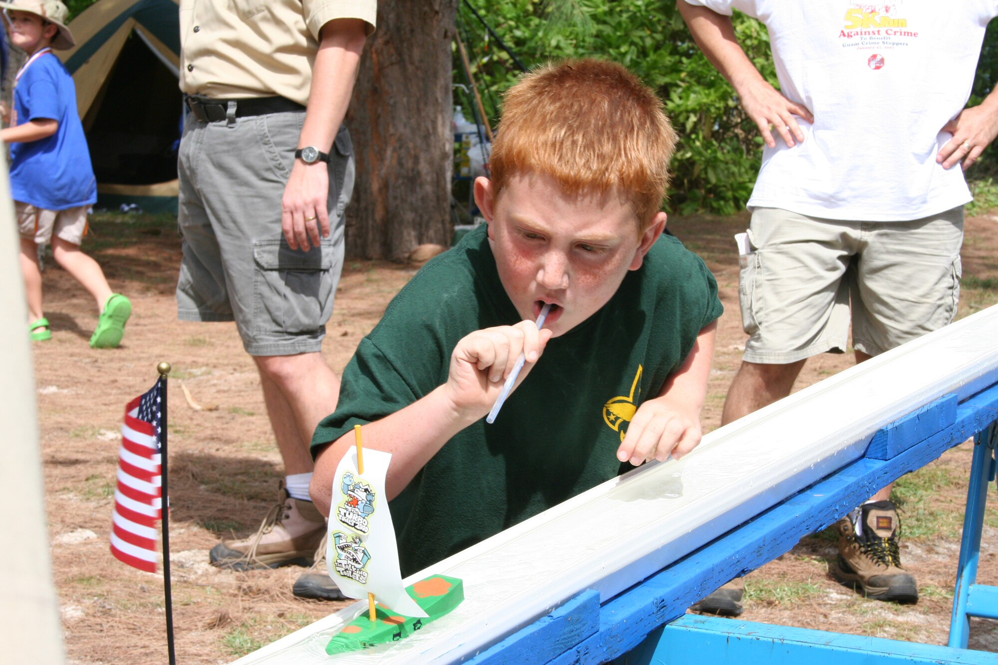 Hayden Grieman, a Bear from Andersen’s Cub Scout Pack 20, blows through a straw, pushing his boat that he made to the end of the rain gutter regatta race, during a recent camping trip to Tarage beach. (Courtesy photo)