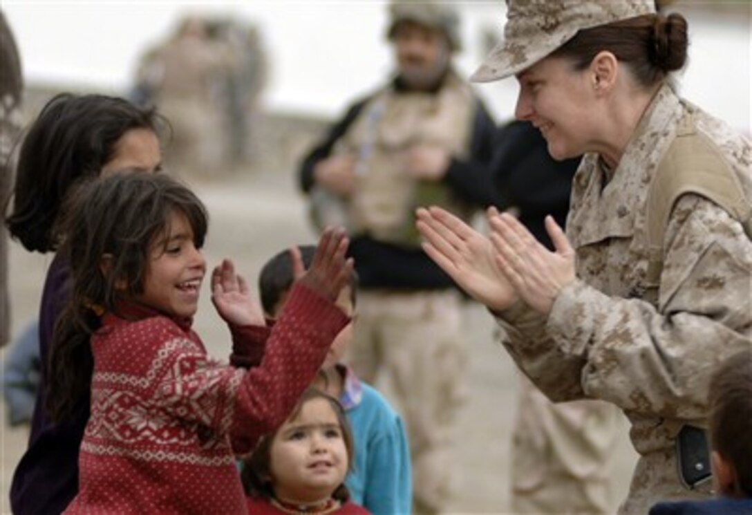 Maj. Shawn Haney, U.S. Marine Corps, plays with a local refugee child during a volunteer community outreach program in Dar Ul Aman, Kabul, Afghanistan, on April 8, 2007.  The program distributes bags filled with clothes, shoes and toys every month with the help of donated items from U.S. citizens.  Haney is a religious cultural affairs mentor at the Human Resource Division within the Combined Security Training Command - Afghanistan.  