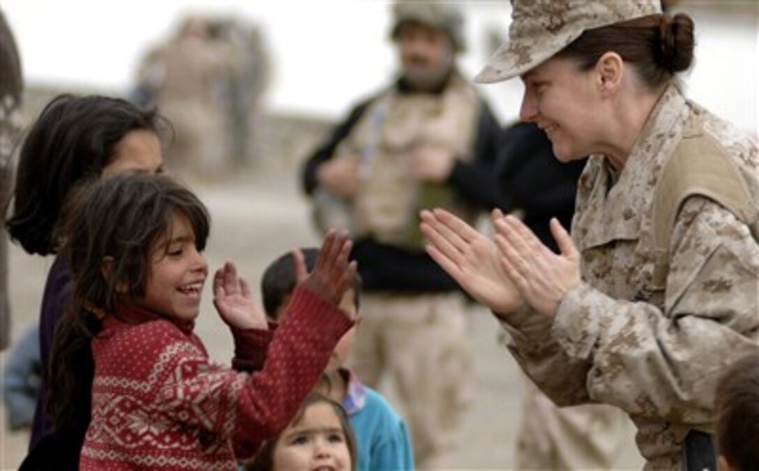 U.S. Marine Corps Maj. Shawn Haney plays with a local refugee child April 8, 2007 in Dar Ul Aman in support of the Volunteer Community Reach Program in Kabul, Afghanistan. Volunteers for the outreach program provided a diversion for the children so that other volunteers could distribute, without distraction, 200 bags of clothes, shoes and toys donated from U.S. citizens.