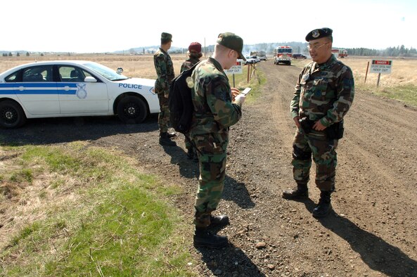 FAIRCHILD AIR FORCE BASE, Wash. -- Tech. Sgt. Roy Miyaji, 92nd Security Forces Squadron patrolman, secures a brush fire site April 6 while Staff Sgt. Larry Carpenter, 92nd Air Refueling Wing Public Affairs, coordinates activities with the Public Affairs deputy chief. The fire started on the explosive ordinance disposal range during Survival School training activities. (U.S. Air Force photo/Airman 1st Class Joshua Chapman)