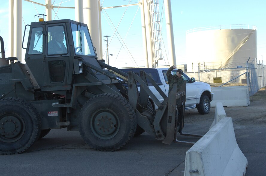 MINOT AIR FORCE BASE, N.D. – Senior Airman Nicholas Richardson guides the tines of a 10k forklift operated by Steve Zimmy under a concrete barrier during the base’s anti-terrorism exercise held here April 9.  As part of the exercise, the concrete barriers are placed at various locations around the installation as an added protective measure.  Airman Richardson and Mr. Zimmy are members of the 5th Civil Engineer Squadron. (U.S. Air Force photo by Airman 1st Class Joe Rivera)