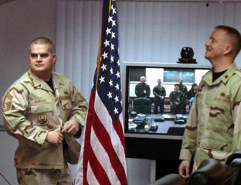 MANAS AIR BASE, Kyrgyzstan – Newly promoted Chief Master Sgt. Craig Dubose, deployed from the 92nd Aircraft Maintenance Squadron at Fairchild Air Force Base, Wash., puts on a new “chiefed” BDU blouse as his wife, Master Sgt. DeeDee Dubose of the 92nd Air Refueling Wing Military Equal Opportunity Office, son Connor, 3, and other Fairchild co-workers look on via video tele-conference. (U.S. Air Force courtesy photo)