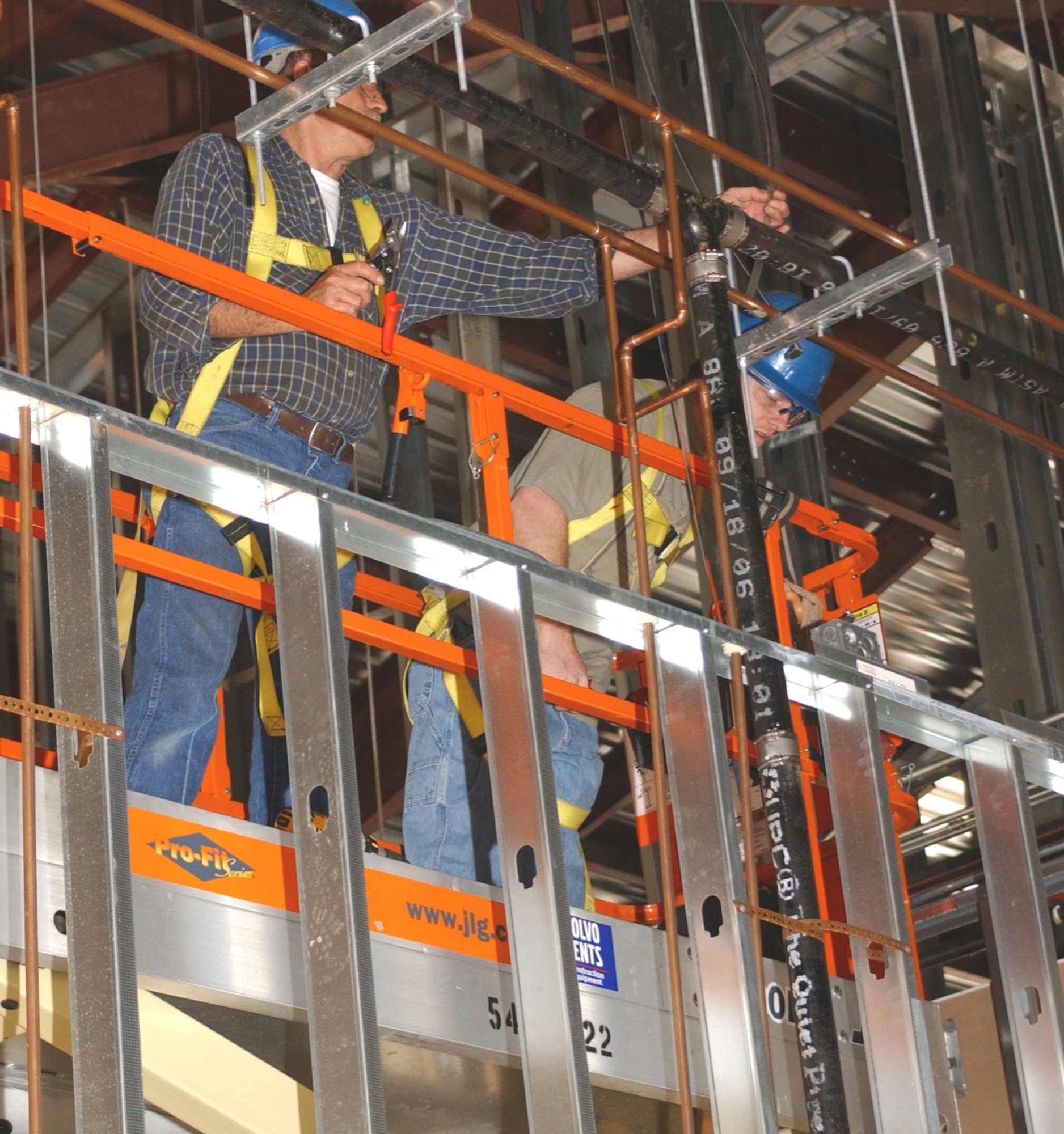 Sheet metal mechanics Sam Nicholson, left, and Charlie Searcy hang straps to secure air conditioning ducts in the service station complex under construction at the corner of Larcher Boulevard and Meadows Drive.  They work for Ray C. Weaver Mechanical Contractors of Gulfport.  (U.S. Air Force Photo by Kemberly Groue)
