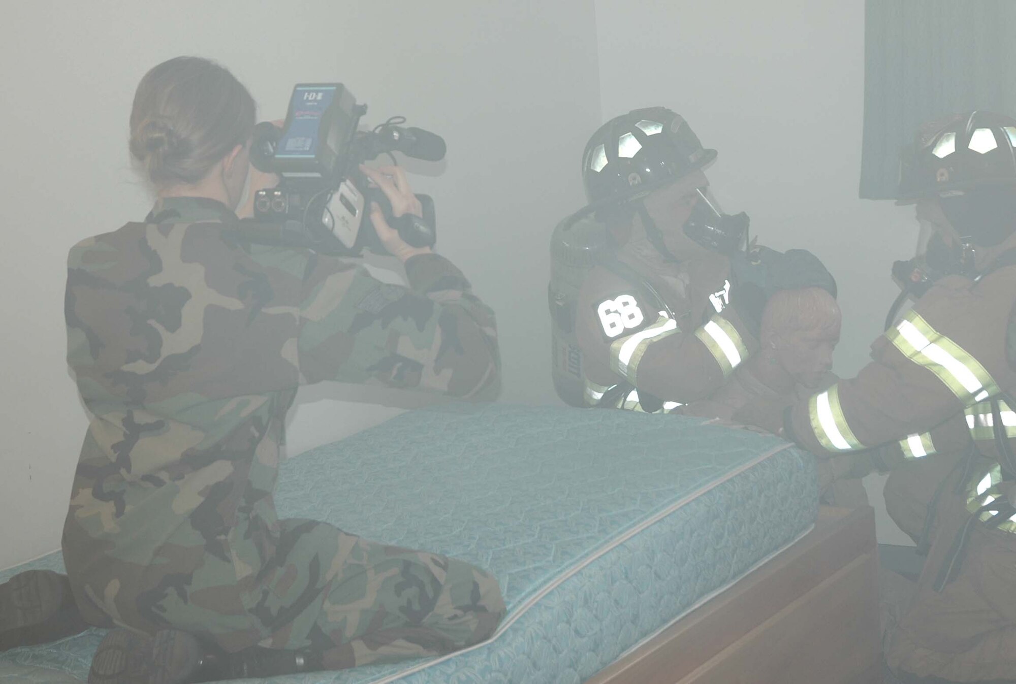 Senior Airman Lana Mills, Air Force News Agency, films members of the 21st Civil Engineer Squadron Fire department during a training exercise April 10.  The firefighters training scenario included entering a smoke-filled dormitory, searching for victims and treating an injured person. "The firefighters will use the training and skills they get here when they deploy," said Master Sgt. Mark Smurda, 21st CES fire department training manager. "Since we train the same way Air Force wide, we fit right in at any deployed unit."  (U.S. Air Force Photo/Staff Sgt. Jessica Switzer)