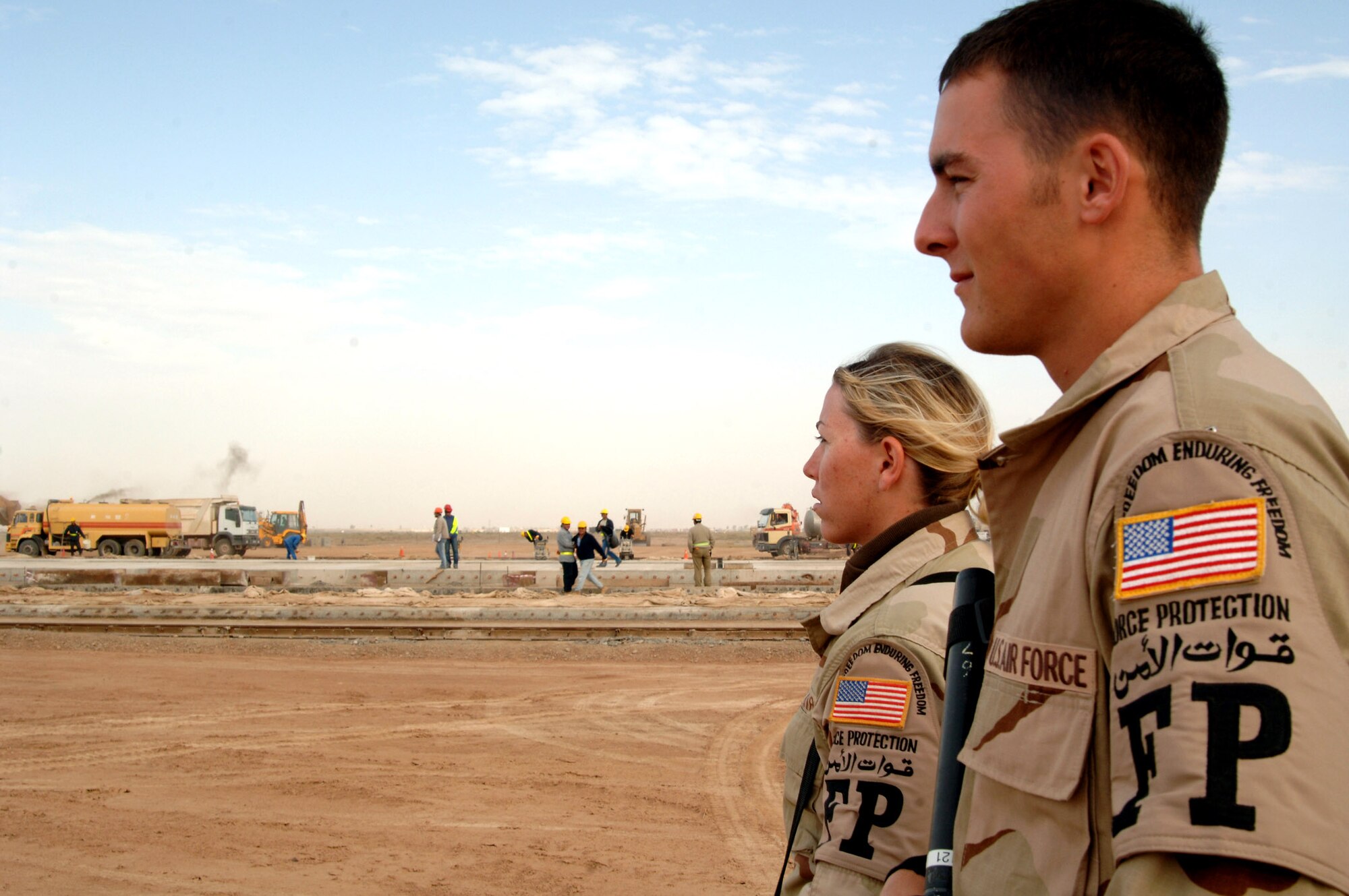 Airman 1st Class Jeremy Roberts and Senior Airman Julia Branch oversee foreign nationals working on the flightline at Balad Air Base in Iraq. As part of their force protection duties, the Airmen search vehicles and do personnel searches, providing escort for third country and local nationals working at Balad. Airman Roberts is deployed from the 91st Missile Maintenance Squadron at Minot Air Force Base, N.D., and Airman Branch is deployed from the 59th Medical Wing at Lackland AFB, Texas. Both Airmen are assigned to the 332nd Expeditionary Security Forces Squadron force protection. (U.S. Air Force photo/Senior Airman Candace Romano)
