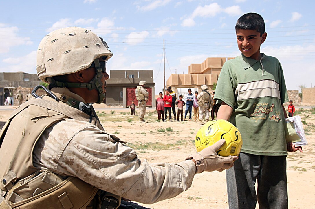 U.S. Navy Seaman Larry J. Threadgill, a corpsman with the Jump Team, 1st Light Armored Reconnaissance Battalion, Regimental Combat Team 2, hands a soccer ball to an Iraqi child during a recent visit to Reyanah, Iraq, March 27, 2007.