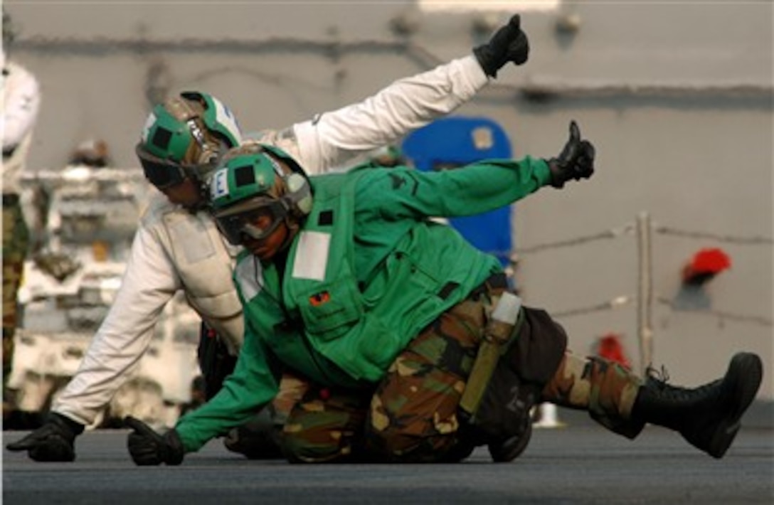 Two U.S. Navy flight deck crewmen, known as final checkers, give the clear to launch signal as an F/A-18F Super Hornet aircraft is prepared to launch from the aircraft carrier USS Harry S. Truman (CVN 75) during flight operations in the Atlantic Ocean on March 28, 2007.  The Truman is underway in the Atlantic Ocean to conduct tailored ship's training availability, a standard used to evaluate a ship's readiness for deployment. 