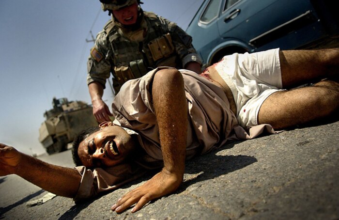 Army Cpl. David Stigers from Bravo Company, 2nd Battalion, 6th Infantry Regiment, 1st Armored Division, Baumholder, GE, administers first aid to an injured Iraqi man that was shot Aug. 16. This is one of several winning photos submitted by Tech. Sgt. Jeremy Lock, 1st Combat Camera Squadron photographer. (U.S. Air Force photo/ Tech. Sgt. Jeremy Lock)