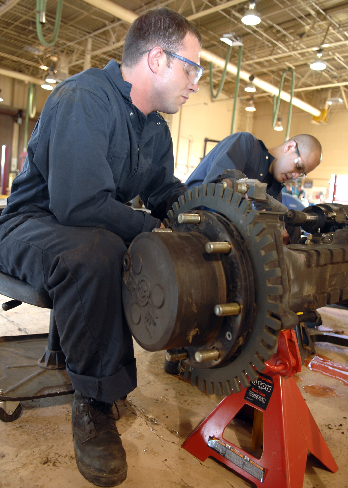 Airman Matthew Hunter and Senior Airman Nicholas Sevaaetasi, 49th Logistics Readiness Squadron, disassembles the front axle on a MB-4 to later replace its parking brakes. (U.S. Air Force photo by Airman 1st Class Jamal Sutter)