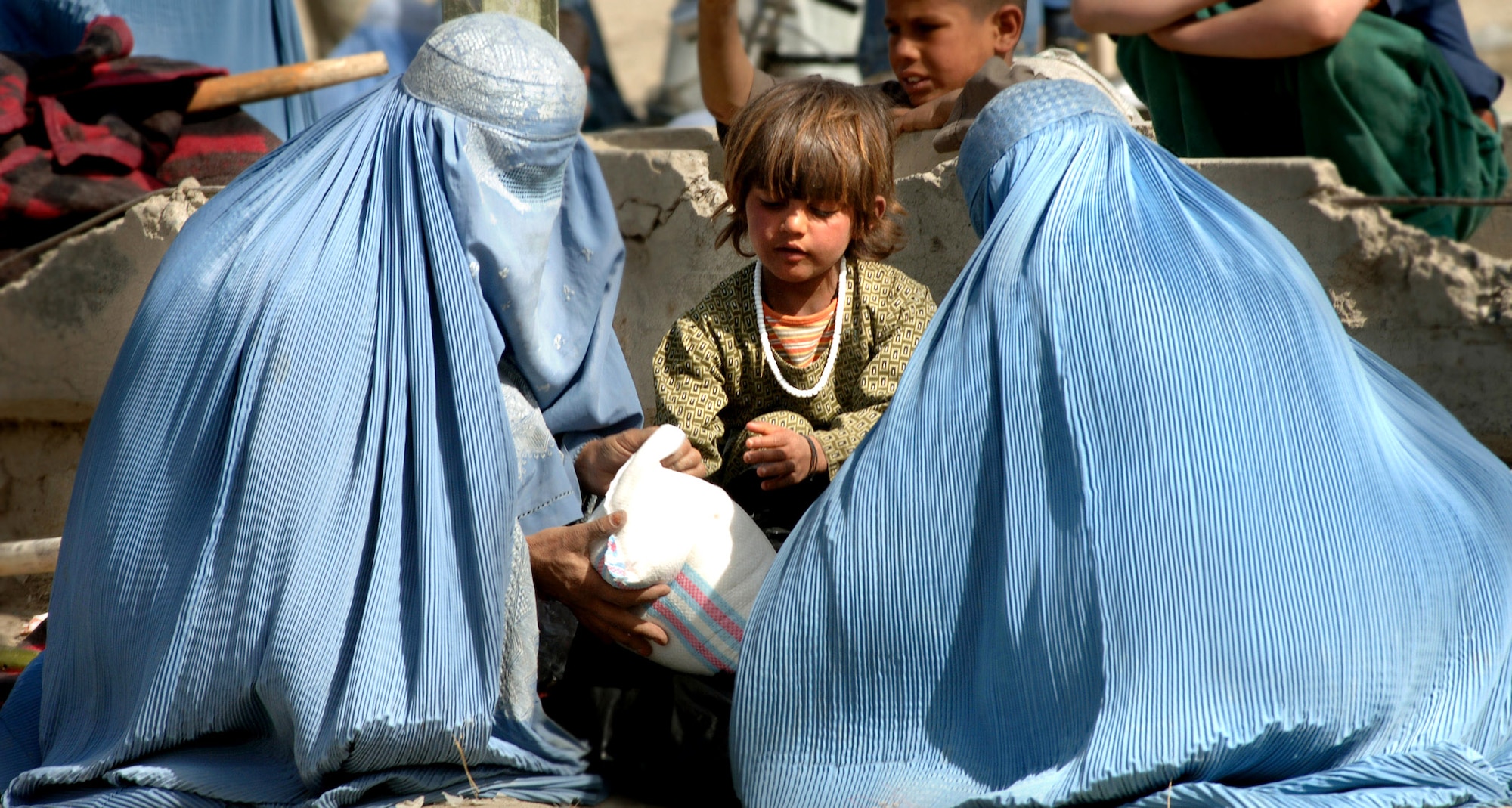 Afghan flood victims go through supplies provided by coalition forces in front of the Afghan Olympic Stadium April 10 in Kabul, Afghanistan. Kabul was ravaged by the first flood in 15 years. The Training Assistance Group from Camp Alamo coordinated food distribution efforts to supply flood victims in Kabul. They provided 100 pounds of rice, beans, wheat, flour ,tea, cooking oil, shovels, sand bags, tarps and more to approximately 100 families. Hundreds of families lost their homes, belongings and supplies to the flood. (U.S. Air Force photo/Tech. Sgt. Cecilio M. Ricardo Jr.) 
