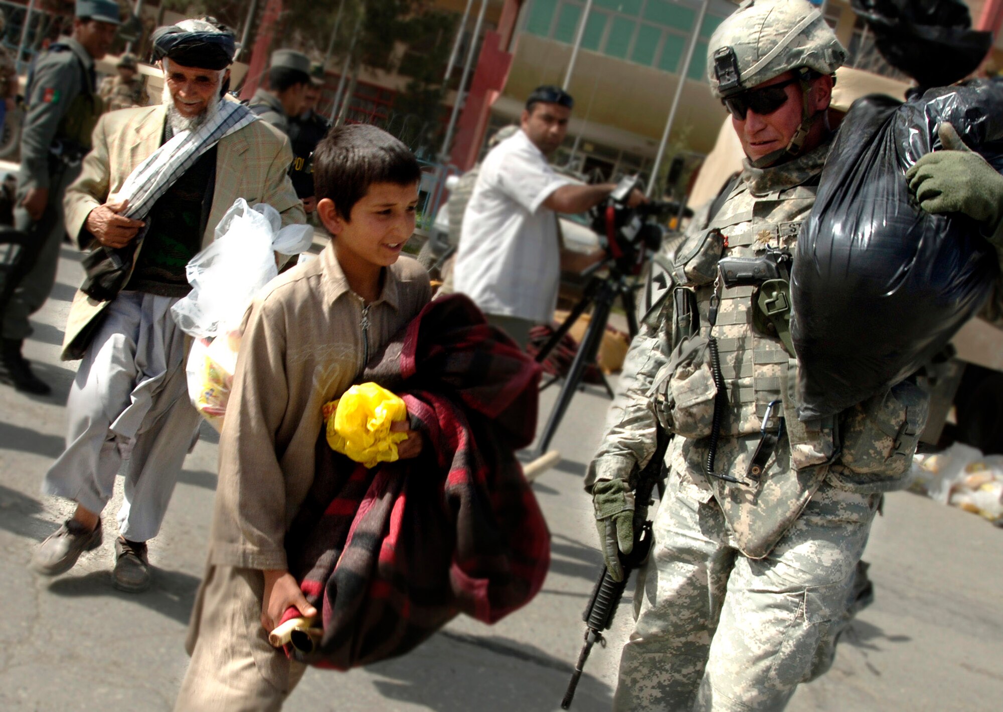 Army Maj. Arnold Strong carries bags of supplies for flood victims in front of the Afghan Olympic Stadium April 10 in Kabul, Afghanistan. Kabul was ravaged by the first flood in 15 years. The Training Assistance Group from Camp Alamo coordinated food distribution efforts to supply flood victims in Kabul. They provided 100 pounds of rice, beans, wheat, flour ,tea, cooking oil, shovels, sand bags, tarps and more to approximately 100 families. Hundreds of families lost their homes, belongings and supplies to the flood. (U.S. Air Force photo/Tech. Sgt. Cecilio M. Ricardo Jr.) 
