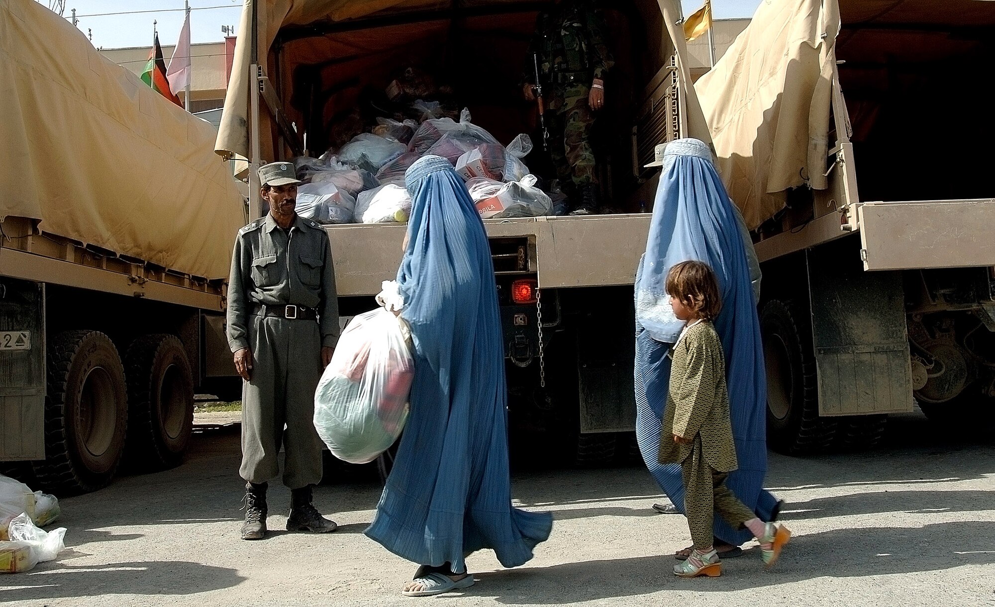 Afghan flood victims receive supplies from coalition forces in front of the Afghan Olympic Stadium April 10 in Kabul, Afghanistan. Kabul was ravaged by the first flood in 15 years. The Training Assistance Group from Camp Alamo coordinated food distribution efforts to supply flood victims in Kabul. They provided 100 pounds of rice, beans, wheat, flour ,tea, cooking oil, shovels, sand bags, tarps and more to approximately 100 families. Hundreds of families lost their homes, belongings and supplies to the flood. (U.S. Air Force photo/Tech. Sgt. Cecilio M. Ricardo Jr.) 
