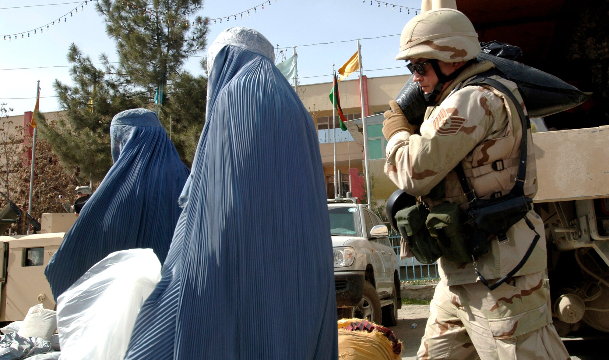 Tech. Sgt. John Asselin carries bags of supplies for flood victims in front of the Afghan Olympic Stadium April 10 in Kabul, Afghanistan. Kabul was ravaged by the first flood in 15 years. The Training Assistance Group from Camp Alamo coordinated food distribution efforts to supply flood victims in Kabul. They provided 100 pounds of rice, beans, wheat, flour ,tea, cooking oil, shovels, sand bags, tarps and more to approximately 100 families. Hundreds of families lost their homes, belongings and supplies to the flood. (U.S. Air Force photo/Tech. Sgt. Cecilio M. Ricardo Jr.)