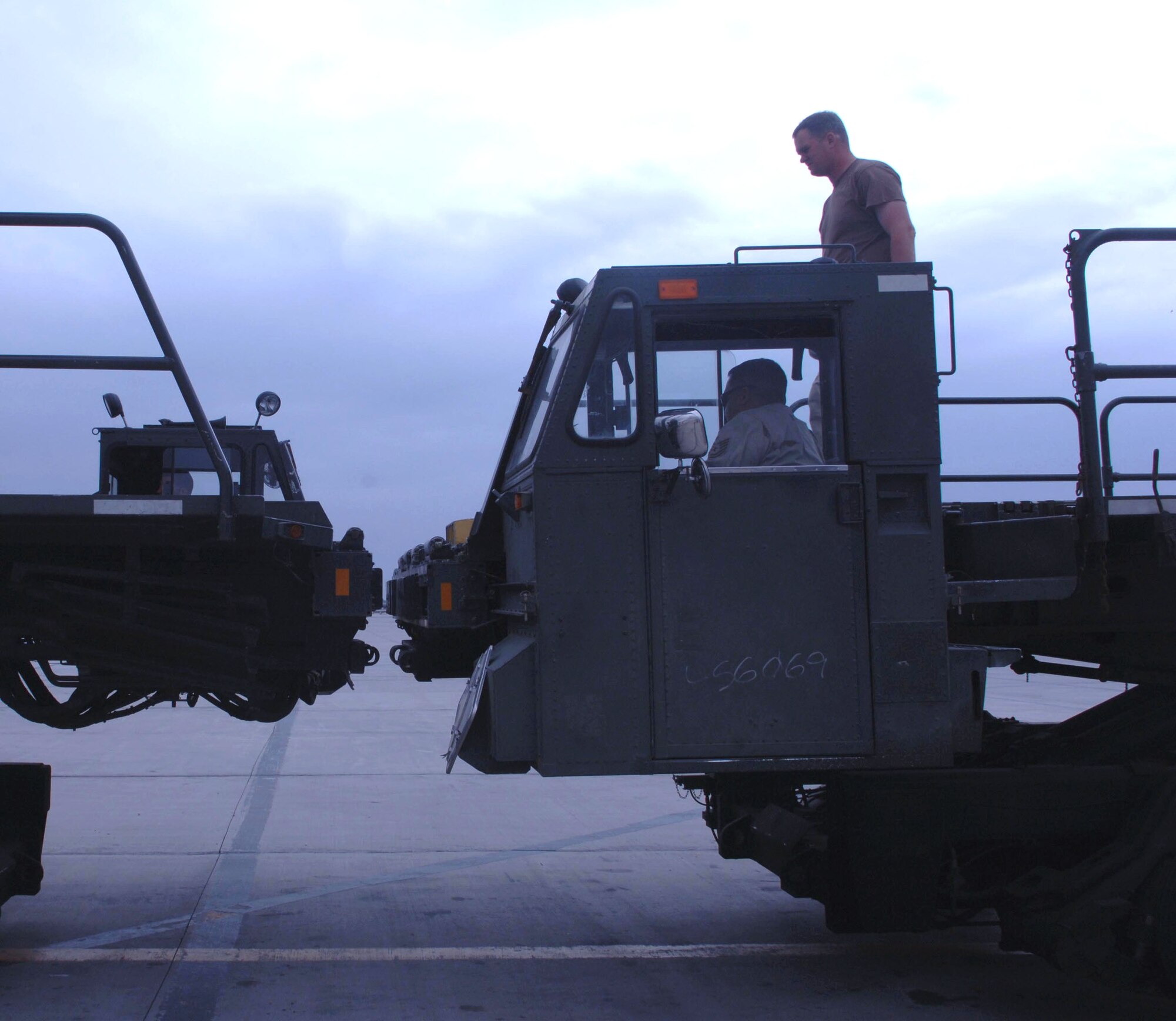 Tech. Sgt. Duane Kaiser stands and guides Tech. Sgt. Luis Quiles as they line up two 60K aircraft cargo loaders for the off-loading of aircraft for Army Force Provider camps April 4 at Bagram Airfield, Afghanistan. The Airmen are with the 455th Expeditionary Logistics Readiness Squadron. (U.S. Air Force photo/Staff Sgt. Kevin Tomko) 
