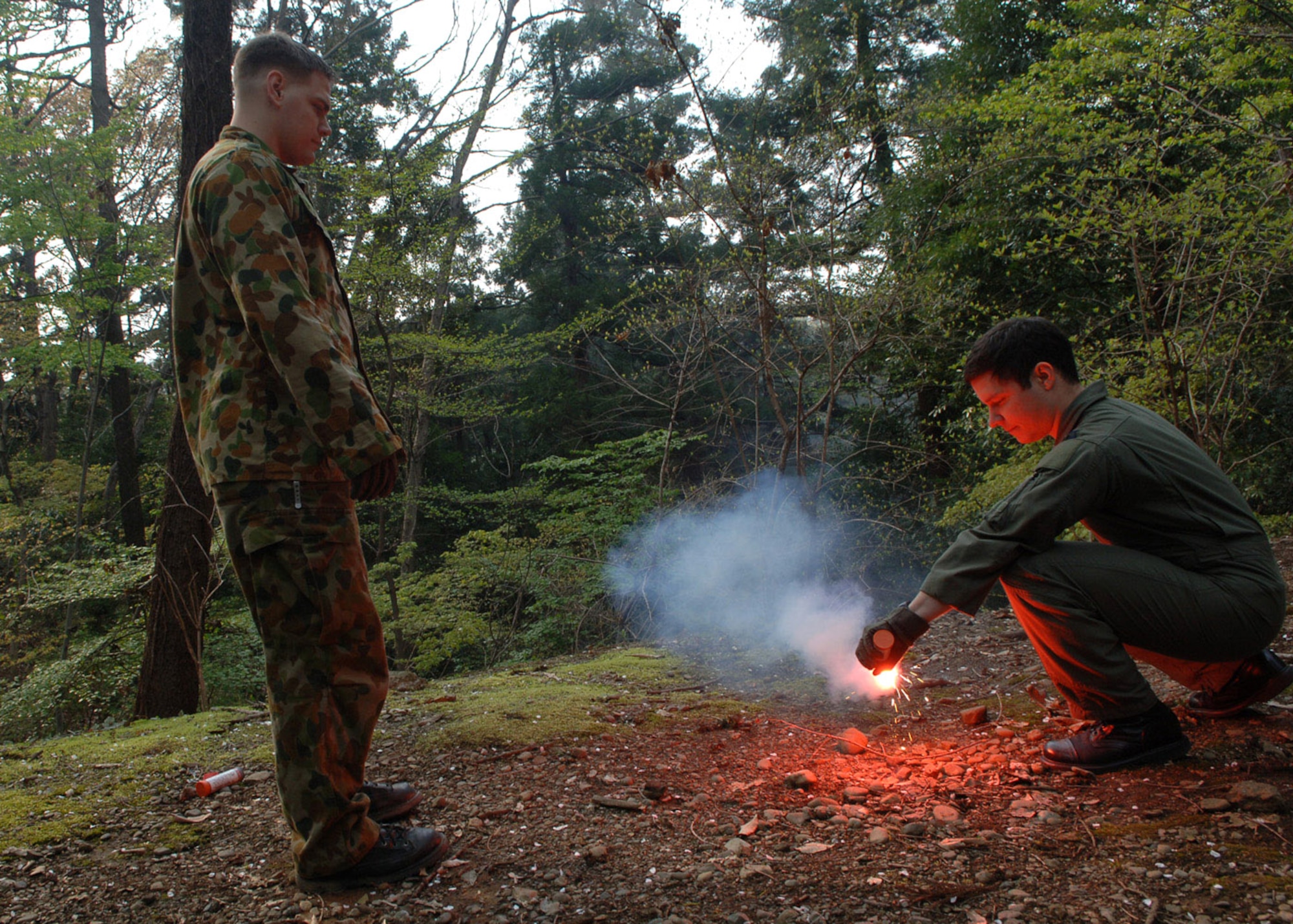 Senior Airman Jason Davis trains Capt. Pierre Alvarado on igniting flares April 10 at the Tama Hills Recreation Center near Yokota Air Base, Japan. Airman Davis is a a survival, evasion, resistance and escape specialist from the 374th Operational Support Squadron, and was recognized as the 2006 Pacific Air Forces SERE Airman of the Year. SERE specialists train members from all branches of the military on how to survive in all environments and conditions. Captain Alvarado is from the 36th Airlift Squadron. (U.S. Air Force photo/Senior Airman Veronica Pierce) 
