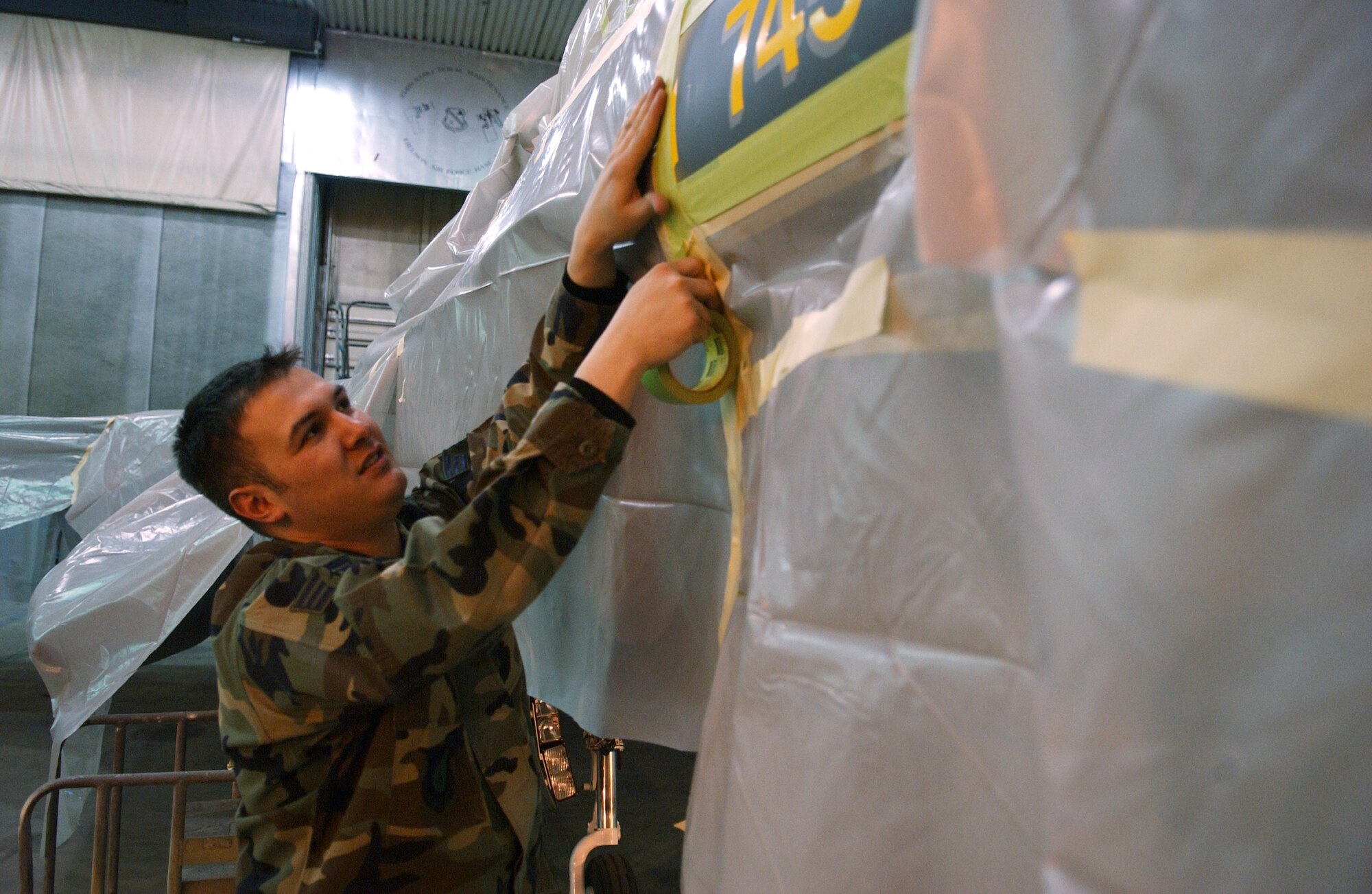 EIELSON AIR FORCE BASE, Alaska -- Senior Airman Francisco Velasquez, 354th Maintenance Squadron, Aircraft Structural Maintenance, masks 'ICEMAN One', the 354th Wing Commanders', F-16 Fighting Falcon on April 11. The new tail design and paint touch up will help prevent future corrosion. (U.S. Air Force Photo by Airman 1st Class Jonathan Snyder)