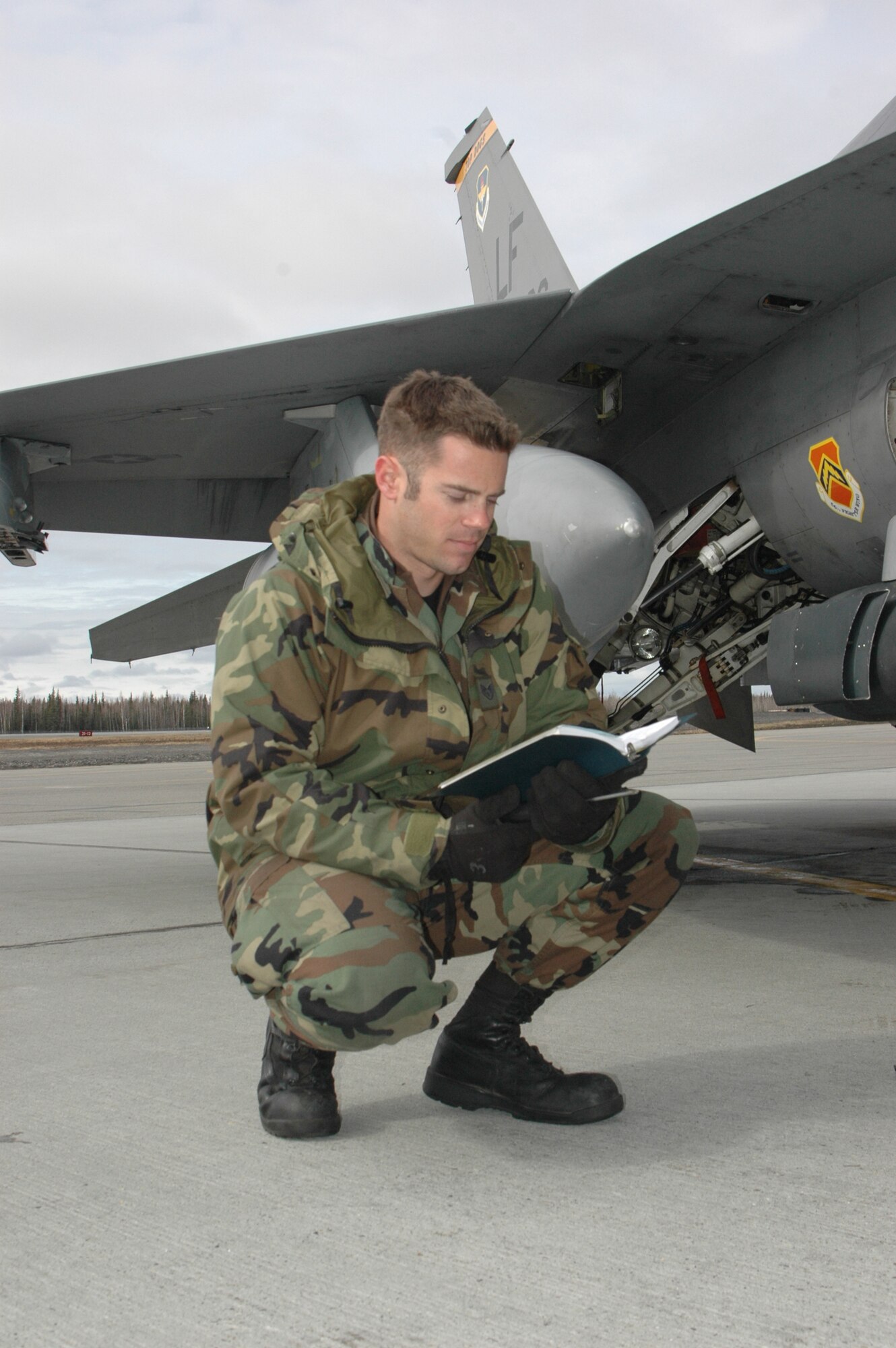 EIELSON AIR FORCE BASE, Alaksa--Staff Sgt. Craig Bair, 61st Fighter Squadron crew chief, reads a checklist before performing routing maintenance on an F-16 on the flight line at Eielson Air Force Base, Alaska during RED FLAG-Alaska 07-1 here April 11. Red Flag-Alaska is a Pacific Air Forces-directed field training exercise for U.S. forces flown under simulated air combat conditions. It is conducted on the Pacific Alaskan Range Complex with air operations flown out of Eielson and Elmendorf Air Force Bases. (U.S. Air Force photo by Tech. Sgt. William Farrow).
