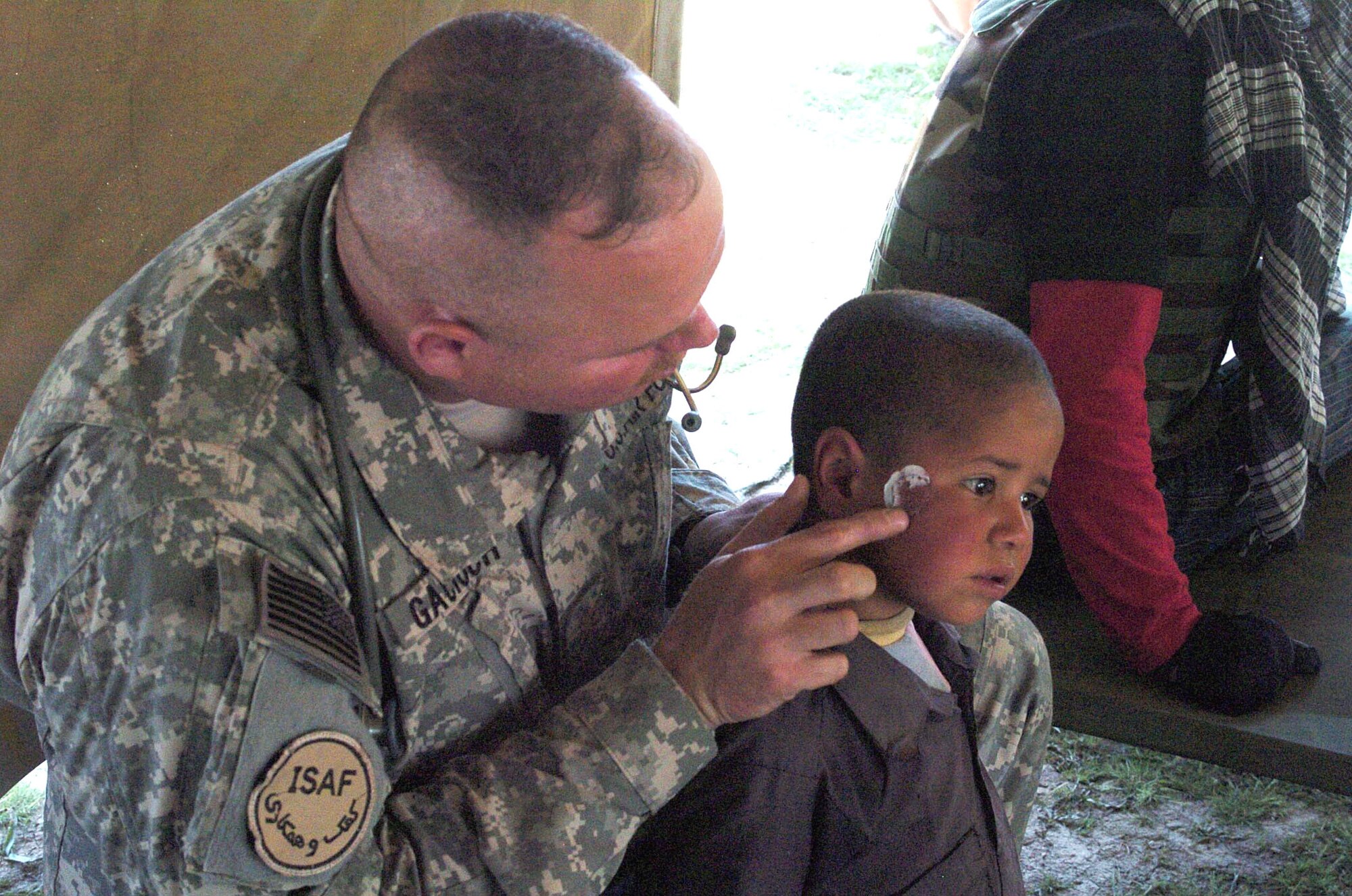 Maj. Tim Gacioch, a physician assistant with the Bagram Provincial Reconstruction Team, treats a young Afghan boy for a fungal infection during a medical civil affairs program visit April 6 in Upper Mousa, Afghanistan. Medics with the Bagram PRT treated ailments ranging from anxiety to ringworm during the day-long event. (U.S. Air Force photo/Staff Sgt. Thomas J. Doscher) 
