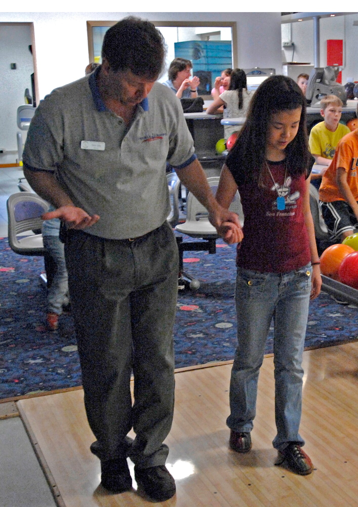 Martin Sibley, Aviano Bowling Center manager, shows Anna Morgan where to position her feet during the Hooked Up 2 Bowling camp at the Aviano Bowling Center April 9. For more information on future bowling classes, call Ext. 7487. (U.S. Air Force photo by Airman 1st Class Liliana Moreno)