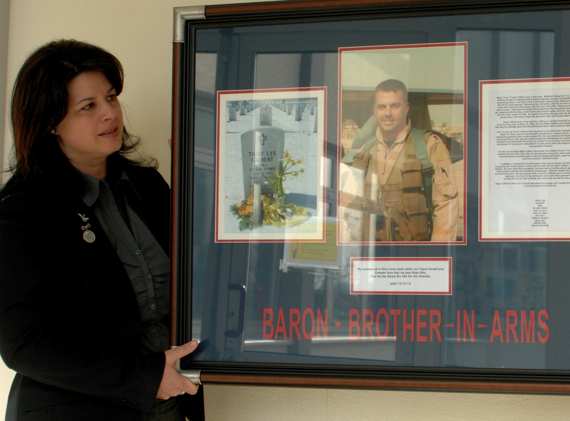 SPANGDHALEM AIR BASE, GERMANY – Lenora Woodcock, event coordinator and spouse William Woodcock, the former 23rd Fighter Squadron commander, helps hang a commemorative plaque hung in the memory of Maj. Troy Gilbert. Major Gilbert graduated from BHS in 1989 feeling a need to serve his country. While serving in support of Operation Iraqi Freedom he lost his life when his F-16 crashed 20 miles northwest of Baghdad. (US Air Force photo by Airman 1st Class Emily Moore)