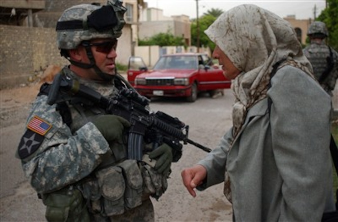 U.S. Army 1st Sgt. Brad Kelley (left) speaks with an Iraqi woman about insurgent activity in the area in Mansour, Iraq, on April 8, 2007, during a combined cordon and search with the Iraqi army.  Kelley is assigned to Blackhawk Company, 1st Battalion, 23rd Infantry Regiment, 3rd Stryker Brigade Combat Team, 2nd Infantry Division.  