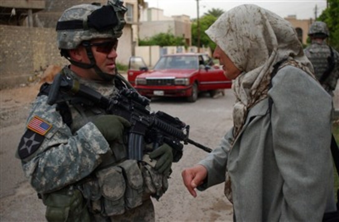 U.S. Army 1st Sgt. Brad Kelley (left) speaks with an Iraqi woman about insurgent activity in the area in Mansour, Iraq, on April 8, 2007, during a combined cordon and search with the Iraqi army.  Kelley is assigned to Blackhawk Company, 1st Battalion, 23rd Infantry Regiment, 3rd Stryker Brigade Combat Team, 2nd Infantry Division.  