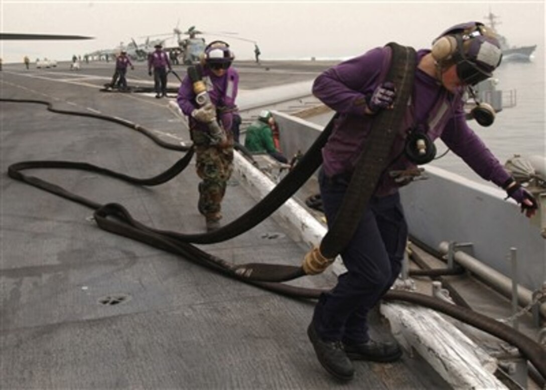 U.S. Navy sailors stow fuel hoses after refueling an F/A-18C Hornet aircraft aboard the USS Dwight D. Eisenhower (CVN 69) on April 11, 2007.  The Eisenhower and embarked Carrier Air Wing 7 are on a regularly scheduled deployment in the Arabian Gulf in support of maritime security operations.  