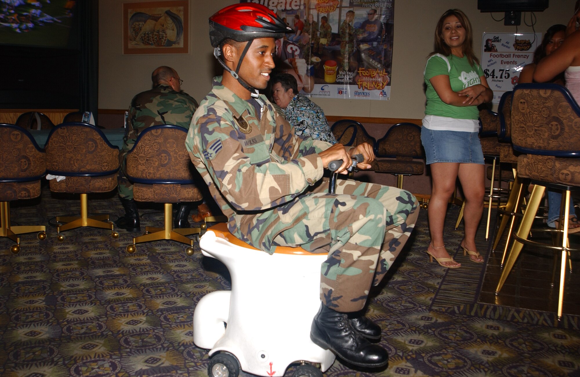 Senior Airman David Wilks, 56th Medical Support Squadron Health Services manager, competes in a toilet racer competition at a Football Frenzy event at the Desert Star Club. (Photo by Airman 1st Class David Bulkley) 