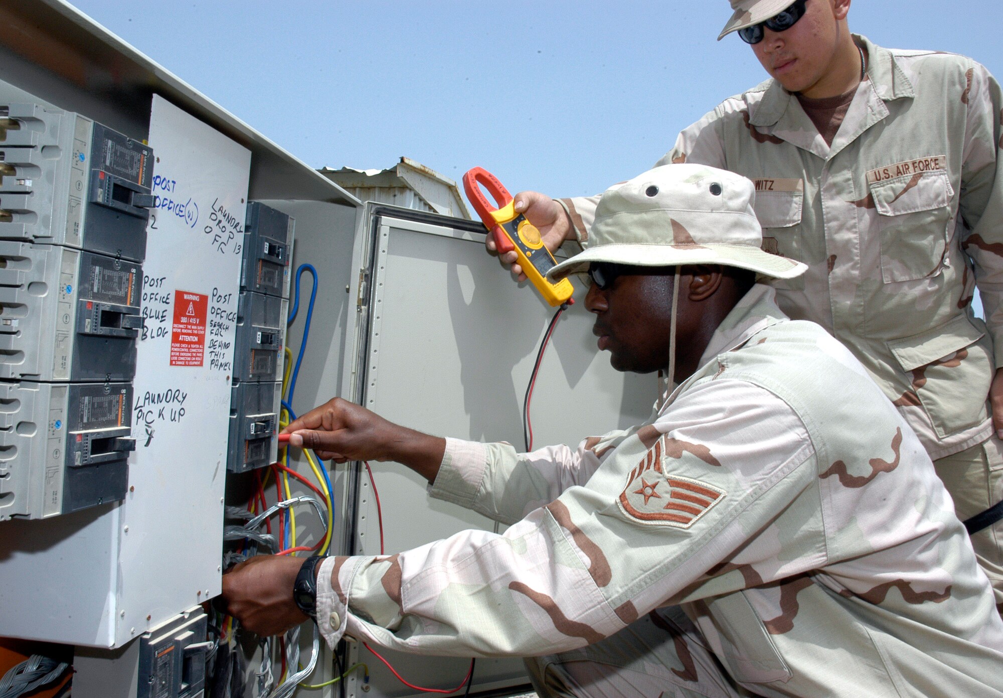 Staff Sgt. Lawrence Beamon uses a multimeter to check the power voltage in a transformer box at Camp Patriot an undisclosed location in Southwest Asia. Senior Airman Jerico Witz assists. Camp Patriot is a camp run for the Army by the Air Force through a "request for forces" arrangement. Members of all branches of the service, to include the Coast Guard, work and reside at the camp. Sergeant Beamon is assigned to the 586th Expeditionary Mission Support Group Civil Engineer Flight. (U.S. Air Force photo/Staff Sgt. Ian Carrier)