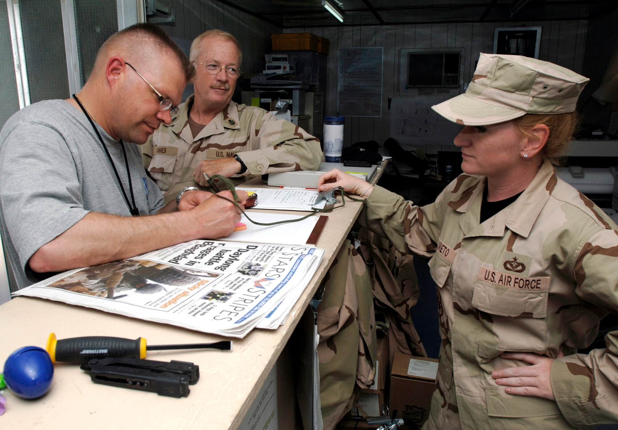 Staff Sgt. Rebecca Diloreto assists Chief Petty Officers Glen Oaks and Stanley Rozum in personnel matters at Camp Patriot an undisclosed location in Southwest Asia. Sergeant Diloreto is an engineering assistant for the 586th Expeditionary Mission Support Group Det. 1. (U.S. Air Force photo/Tech. Sgt. Edward D. Holzapfel)