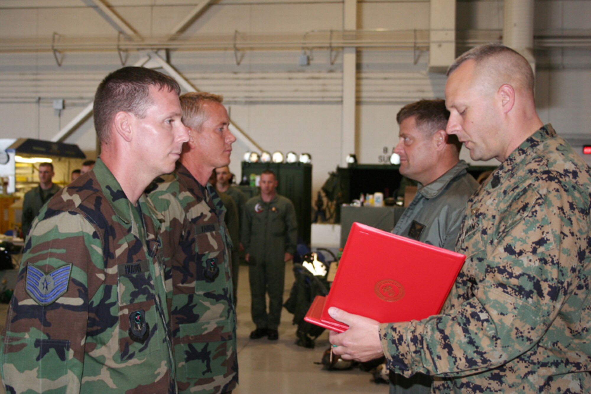 Tech. Sgt. Dennis Hudon (front left) and Master Sgt. James Vaughan, 8th Aircraft Maintenance Unit, stand at attention while Marine Sergeant Major Stephen Balczo (front right), Marine Medium Tiltrotor Training Squadron 204, reads the Navy and Marine Corps Achievement Medal citations, and Marine Col. Mark Clark, VMMT 204 commanding officer, waits to pin the medals on the Airmen. The Airmen were presented the medals in a surprise ceremony April 5 in Independence Hangar. (U.S. Air Force photo by Staff Sgt. Angela Shepherd)