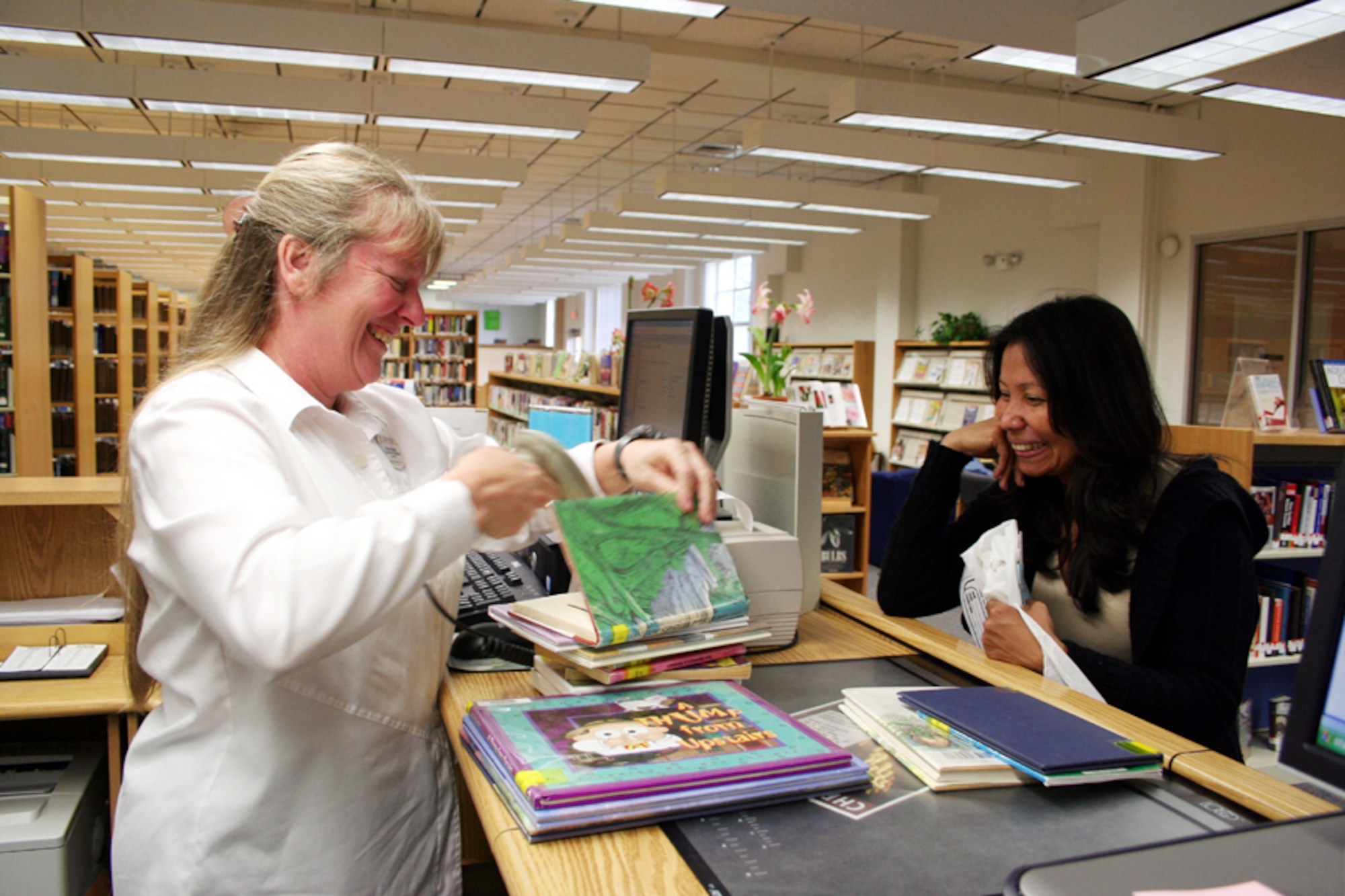 Sabrina Honda (left), 1st Special Operations Services Squadron, checks out a book for a library patron April 9. Ms. Honda was named the Federal Library Technician of the Year for 2006. (U.S. Air Force photo by Jamie Haig)