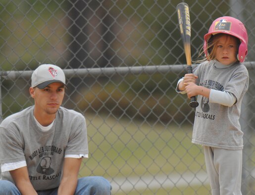 Autumn Freehoffer, daughter of Staff Sgt. Noah Freehoffer, awaits a pitch as Steven Stewart, 23rd Logistics Readiness Squadron, performs umpire duties during the first Moody youth baseball game of the season April 10. (U.S. Air Force photo by Staff Sgt. Joshua Jasper)
