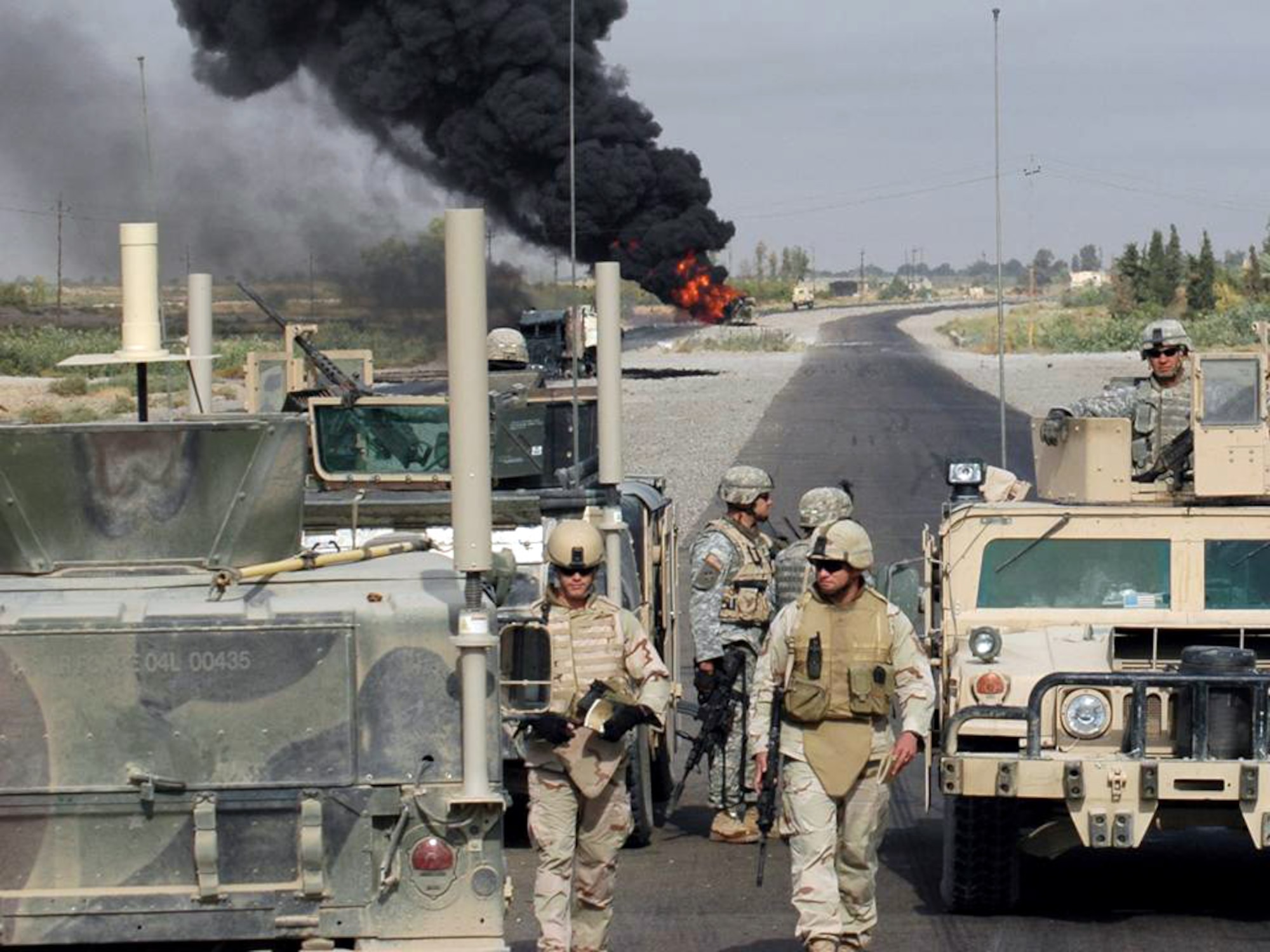 Waiting for Explosive Ordnance Disposal to confirm the scene is safe, Staff Sgt. Christopher Hawks (left) and Master Sgt. Albert Schneider (right), prepare to collect evidence and obtain pictures. The EOD team from Paliwoda, Iraq, and Sergeant Schneider's Weapons Intelligence Team had just arrived at the scene of two improvised explosive devices detonations targeting civilian vehicles on Main Supply Route Tampa. (U.S. Air Force photo)