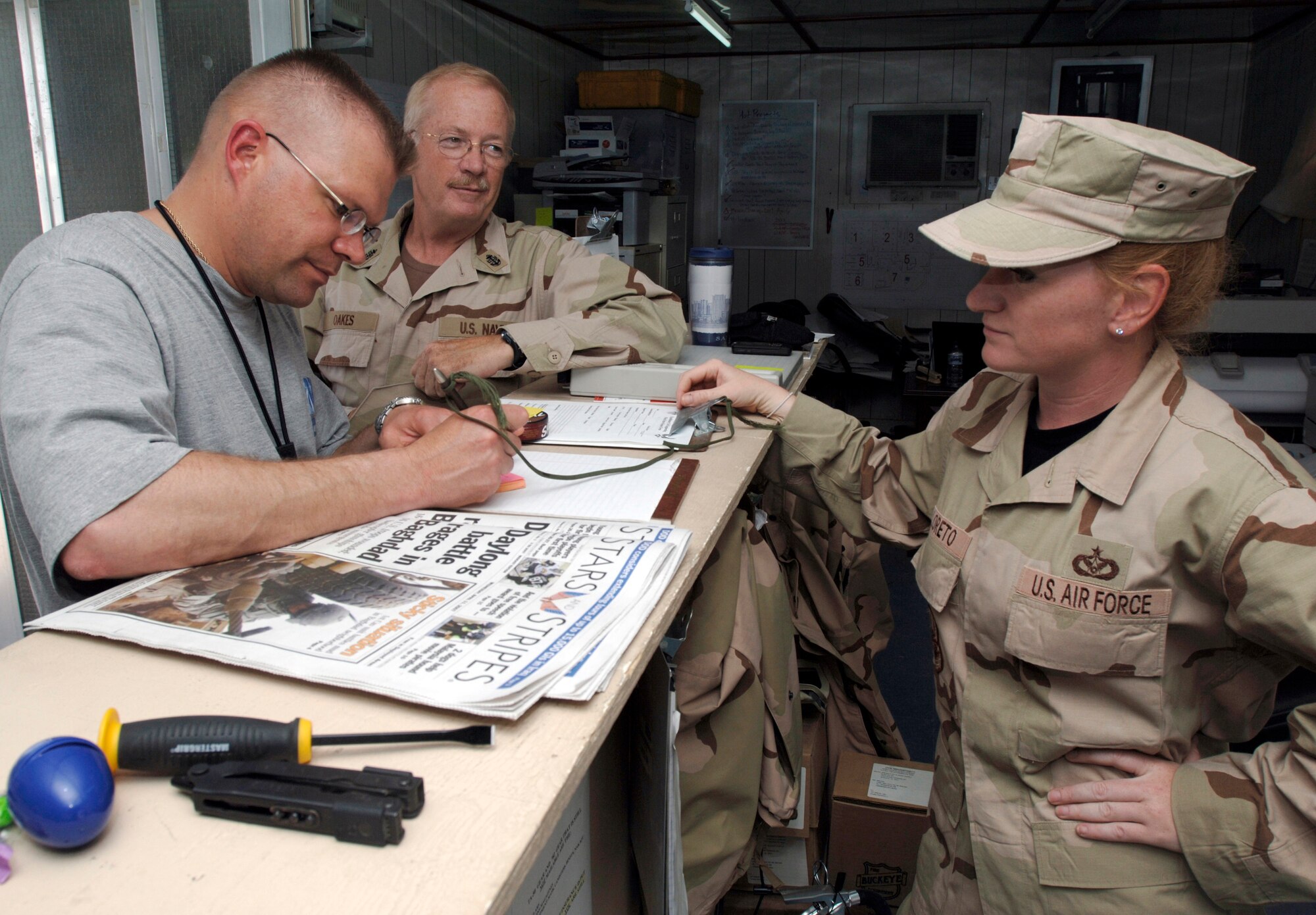 SSgt Rebecca S. Diloreto an engineering assistant for the 586th Expeditionary Mission Support Group Detachment 1 at an undisclosed location in Southwest Asia assists CPO Glen A. Oaks out process and CPO Stanley E. Rozum in process completing this phase of their rotation. (U.S. Air Force photo by Tech. Sgt. Edward D. Holzapfel) (Released)