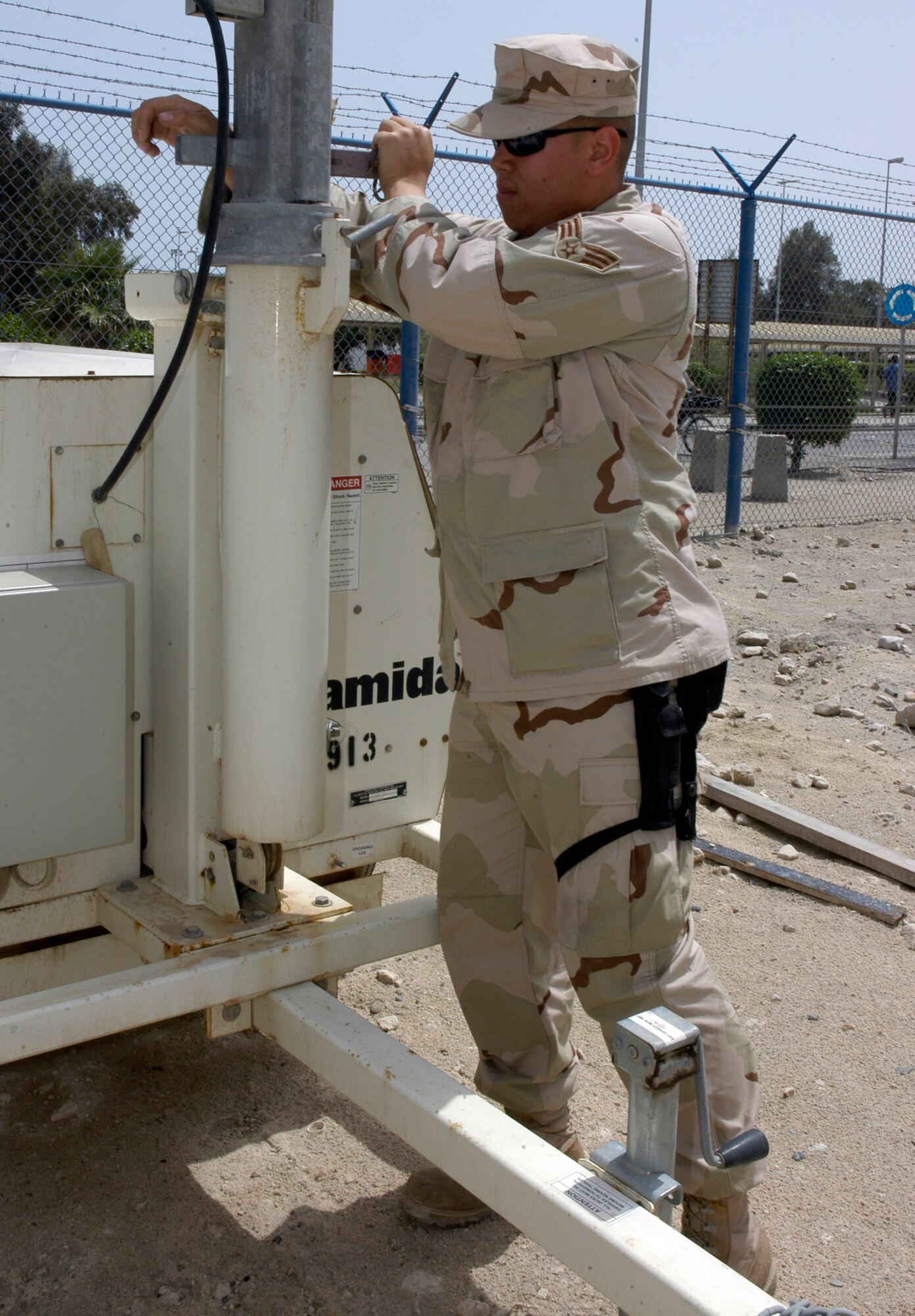SOUTHWEST ASIA -- Senior Airman Jerico Witz, 586th Expeditionary Mission Support Group Civil Engineeering Flight, uses a hand-crank to raise a generator-powered floodlight at Camp Patriot. Camp Patriot is a camp run for the Army by the Air Force through a Request for Forces arrangement. Members of all branches of the service, to include the Coast Guard, work and reside at the camp. (AF photo/Staff Sgt. Ian Carrier)                                                             