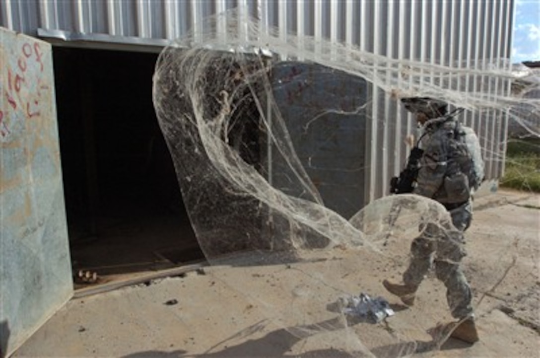 Cobwebs billow out of a warehouse after U.S. Army soldiers opened the doors during a raid near Sharqat, Iraq, on April 3, 2007.  The soldiers are from Alpha Company, 5th Battalion, 82nd Field Artillery Regiment.  