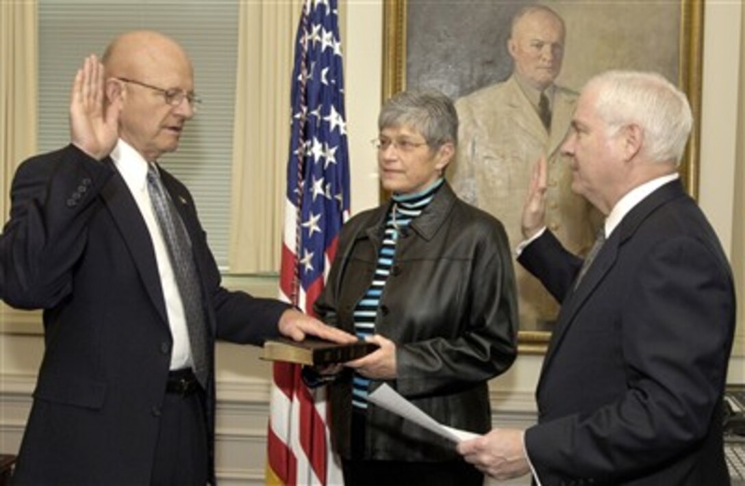 Retired U.S. Air Force Lt. Gen. James R. Clapper (left) is sworn-in as under secretary of defense for intelligence by Secretary of Defense Robert M. Gates (right) during a private ceremony in the Pentagon on April 13, 2007.  Clapper's wife holds the Bible as the oath of office is administered. 