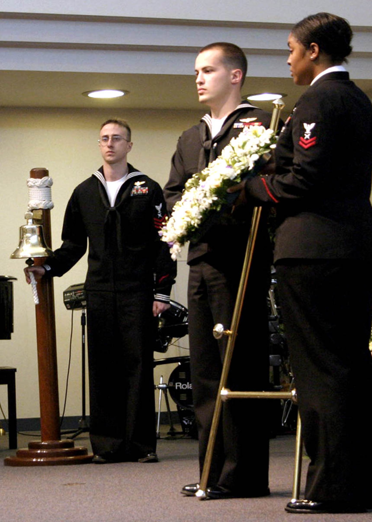070413-MISAWA AIR BASE, Japan -- Petty Officer 1st Class Erich Keough (left), prepares to ring the Navy Bell, while Petty Officers 2nd Class Ryan Dacy and Sharieca Claving, lay the wreath during the Two-Bell Ceremony in the Misawa Main Chapel here April 13. The ceremony is held annually to honor 30 Sailors and one Marine who perished in the Sea of Japan after their Navy EC-21 reconnaissance aircraft was shot down by two North Korean MIG's on April 15, 1969. The petty officers are assigned to Navy Information Operations Command. (U.S. Air Force photo by Staff Sgt. Vann Miller)