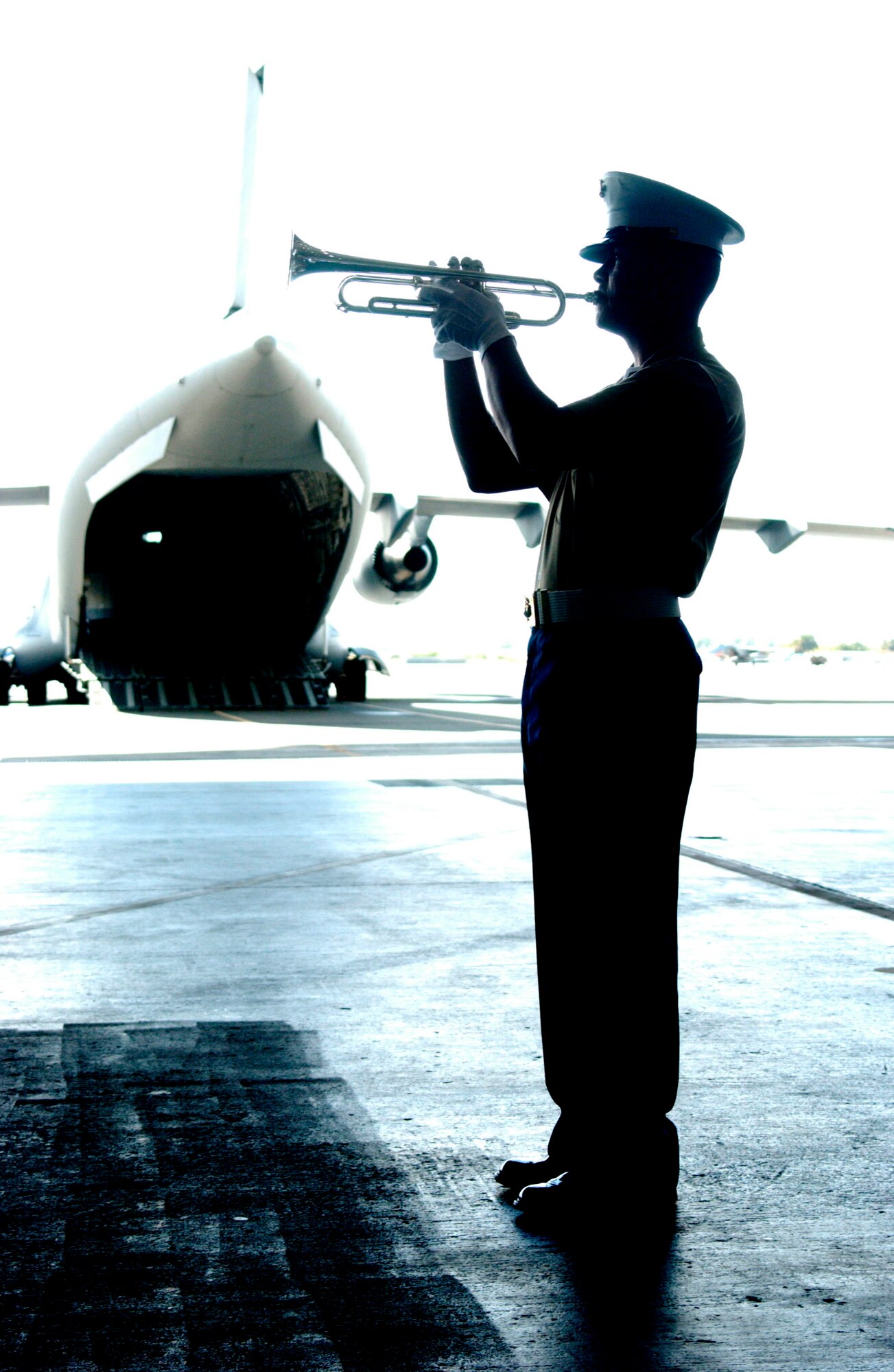 HICKAM AIR FORCE BASE, Hawaii -- A bugler sounds taps as the remains of six Korean War veterans are carried by a joint military honor guard here April 12. A ceremony to honor the remains believed to be those of six U.S. service members lost during the Korean War marks their return to American soil at Hangar 35 on Hickam Air Force Base. The remains were turned over by North Korean officials to a U.S. delegation earlier this week. (Air Force photo by Angela Elbern)