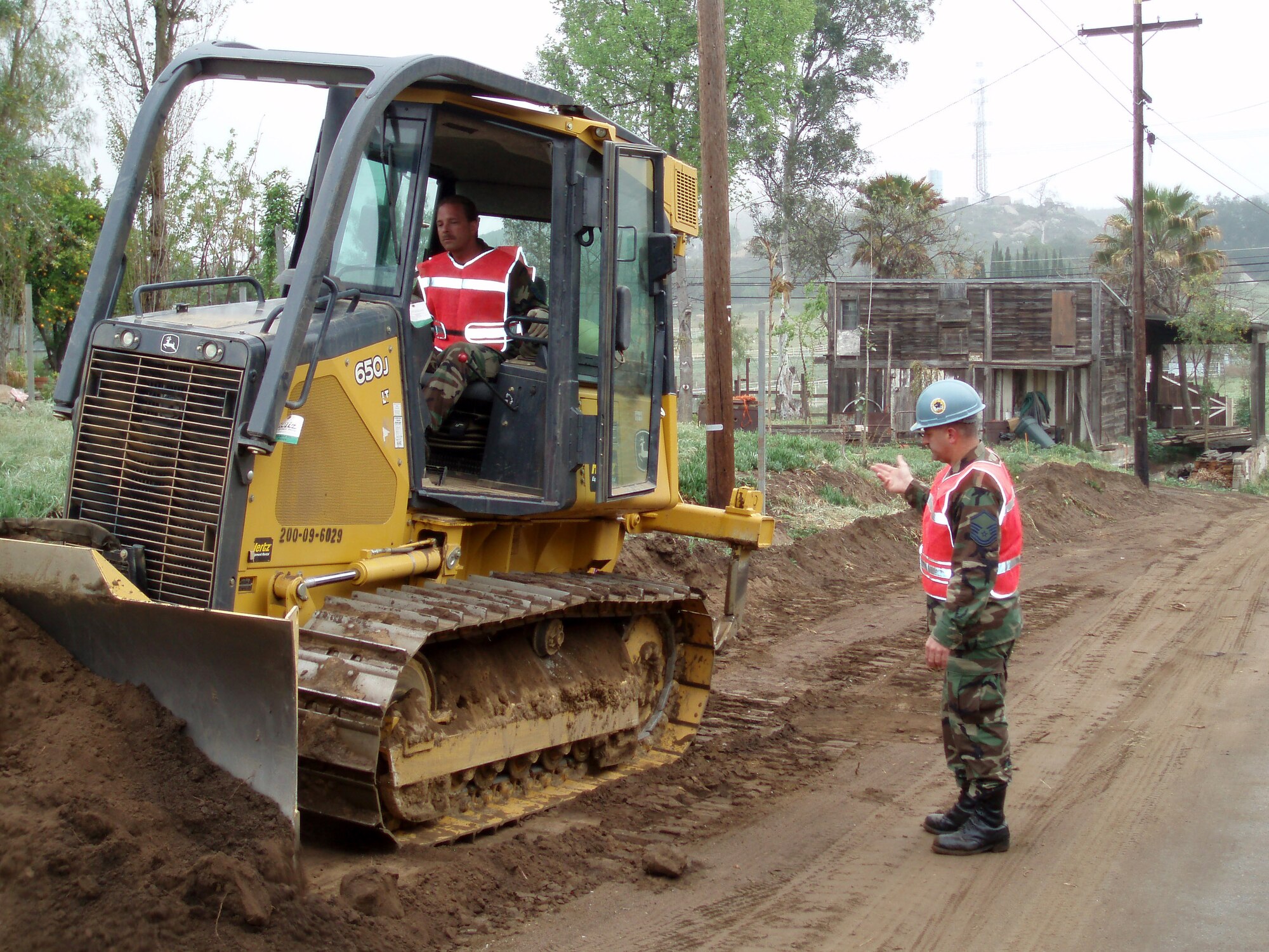 ESCONDIDO, Calif. --  Master Sgt. Moises Zanazanian directs Tech. Sgt. Mark Boganski using a bulldozer blade to scrape topsoil while widening a road for the San Pasqual Band of Mission Indians. Both are from members of the 439th Civil Engineering Squadron, Westover Air Reserve Base,

