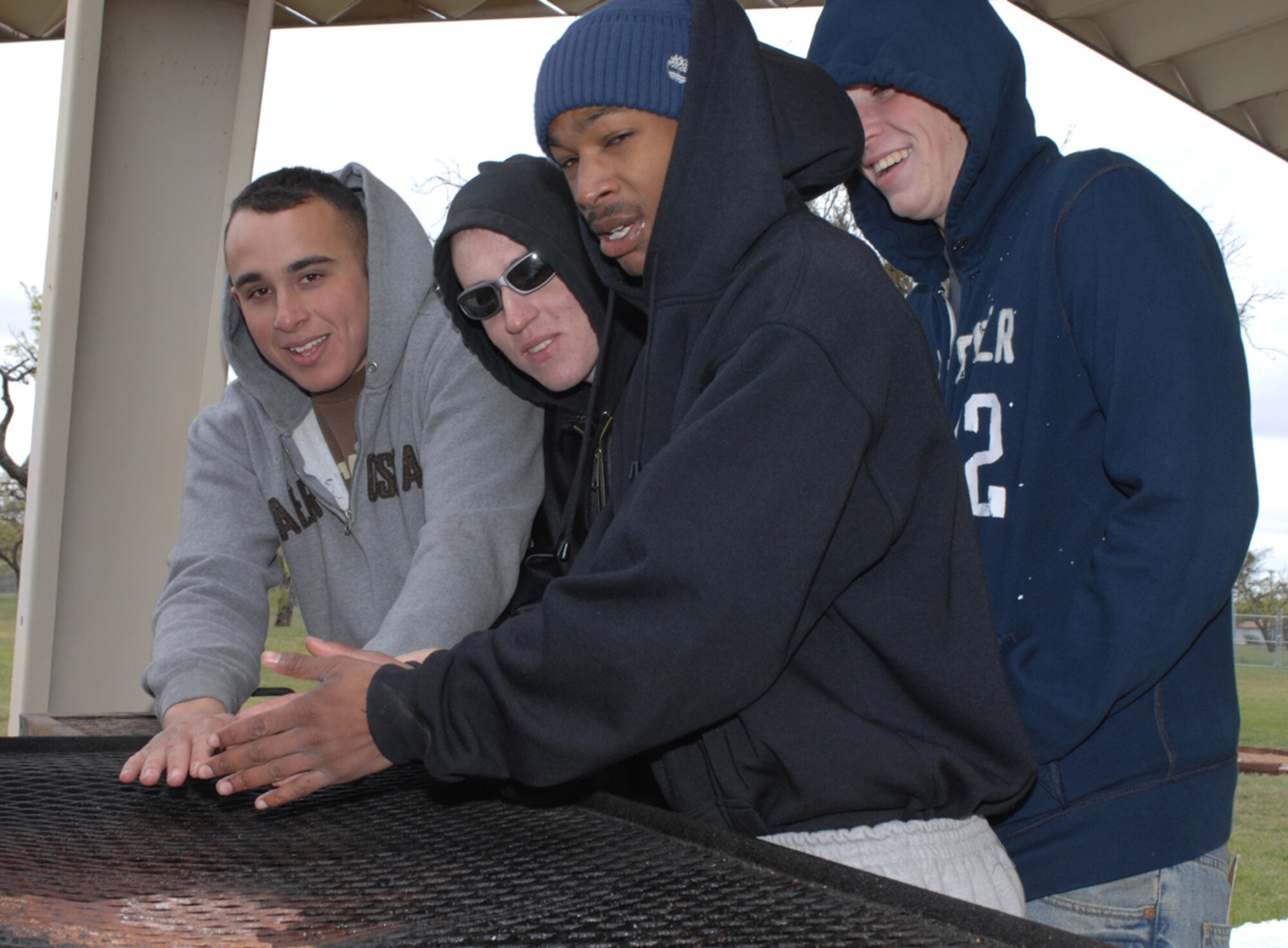 (From left to right) Airmen 1st Class Robert Osteen, Matt Schellinger, Donald Keeper, and Scott Esler try to keep warm while volunteering at "Shoppin' in the Park" April 14. The Airmen made sure that everything was in order and everyone was in the right spots, making the community event successful and fun. (U.S. Air Force photo by Amn Jennifer Romig)